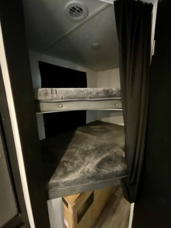Inside an RV rental: a compact sleeping area with two built-in bunk beds and mattresses, ideal for travelers.. Coachmen Freedom Express Ultra Lite 238BHS 2022
