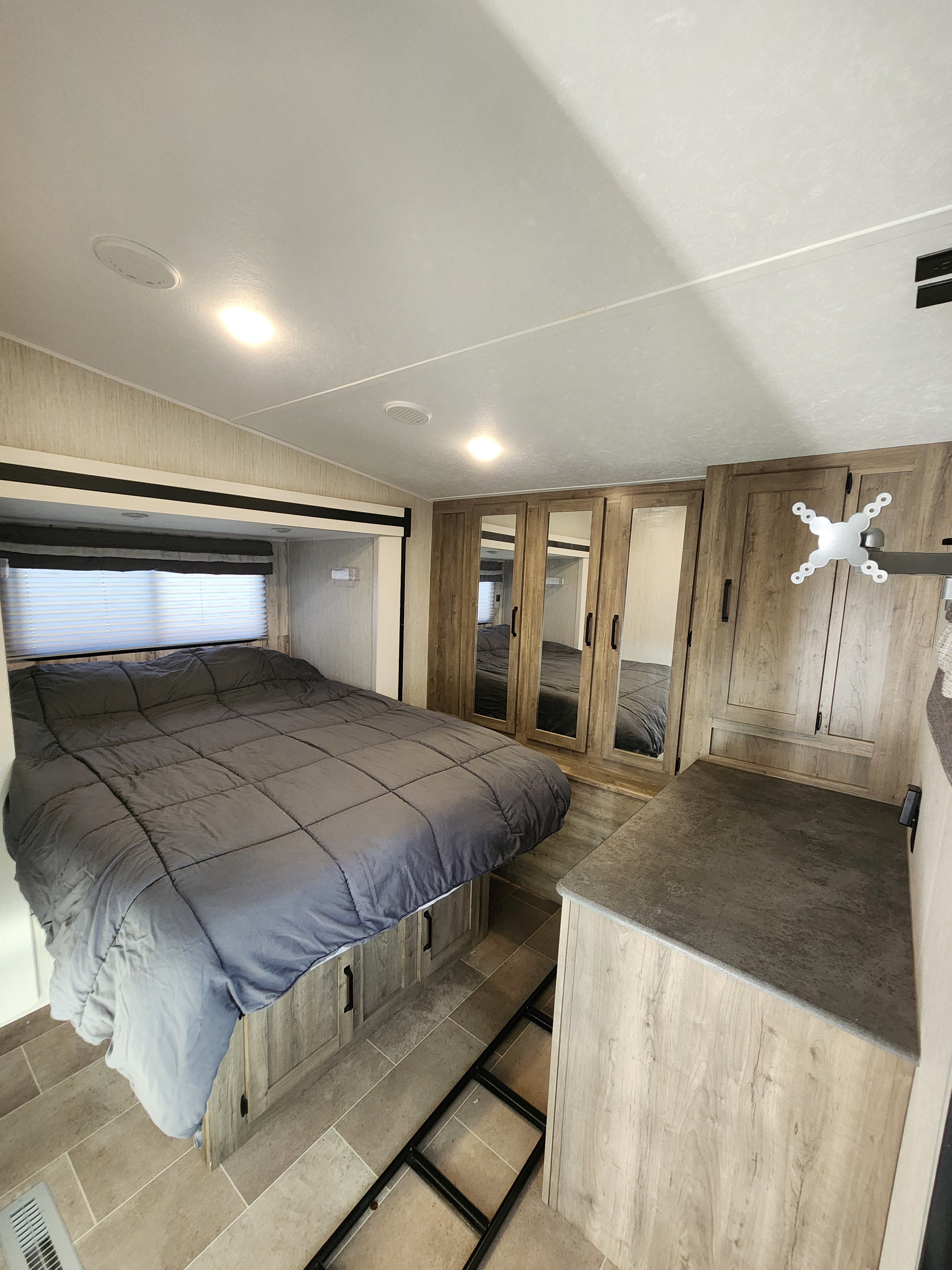 Inside an **RV rental**: a modern bedroom with a comfortable bed, mirrored closets, and built-in storage.. Palomino Puma 2021