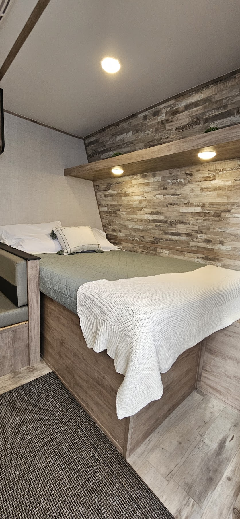 This RV rental offers a comfy bedroom with textured wood walls, shelf lighting, and a soft bed for a restful journey.. Gulf Stream Ameri-Lite LE 2023