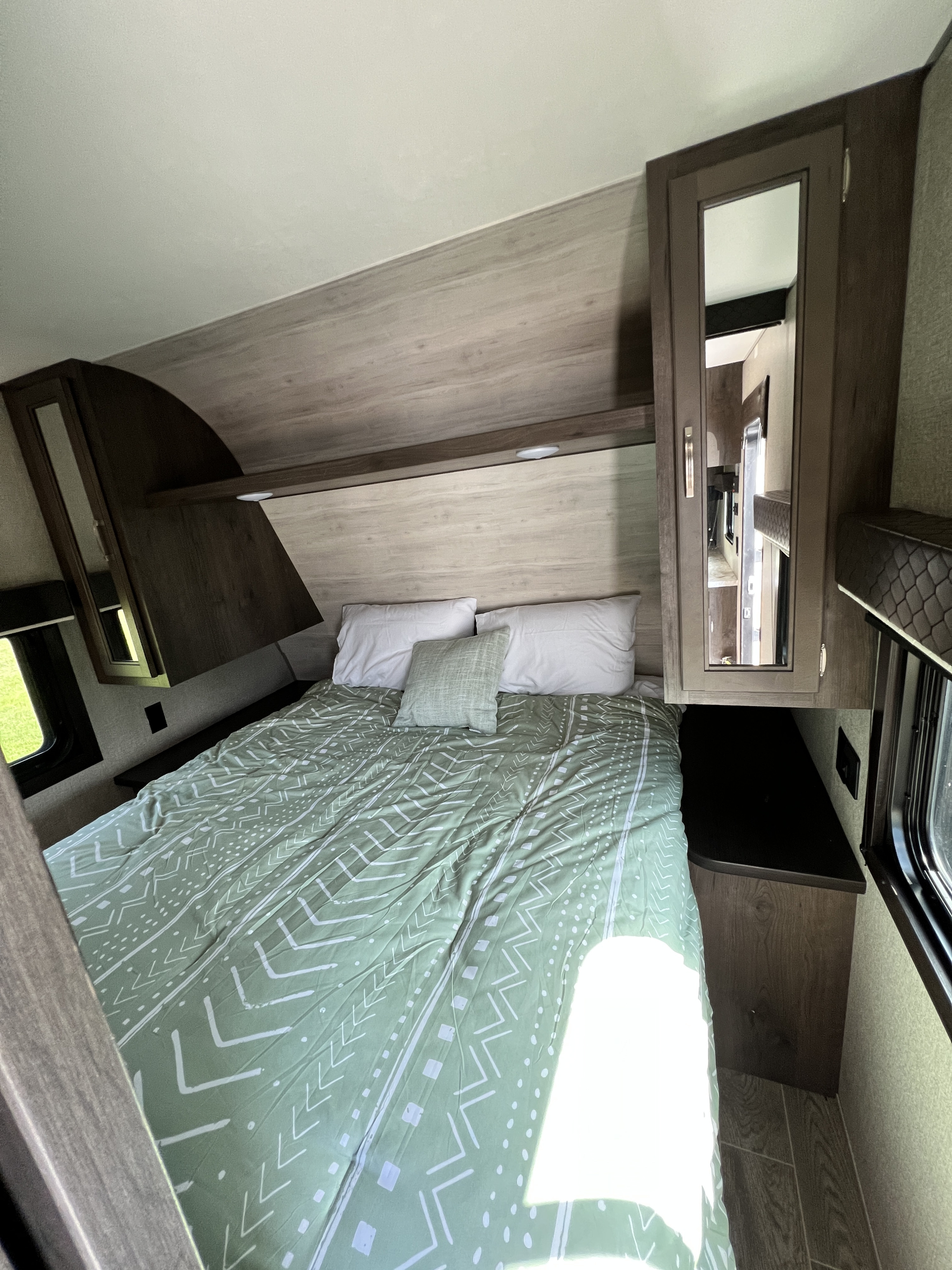 Cozy RV rental bedroom with a green patterned bed, ample storage, and mirrored cabinet. Modern and clean design.. Jayco Jay Flight SLX 2021
