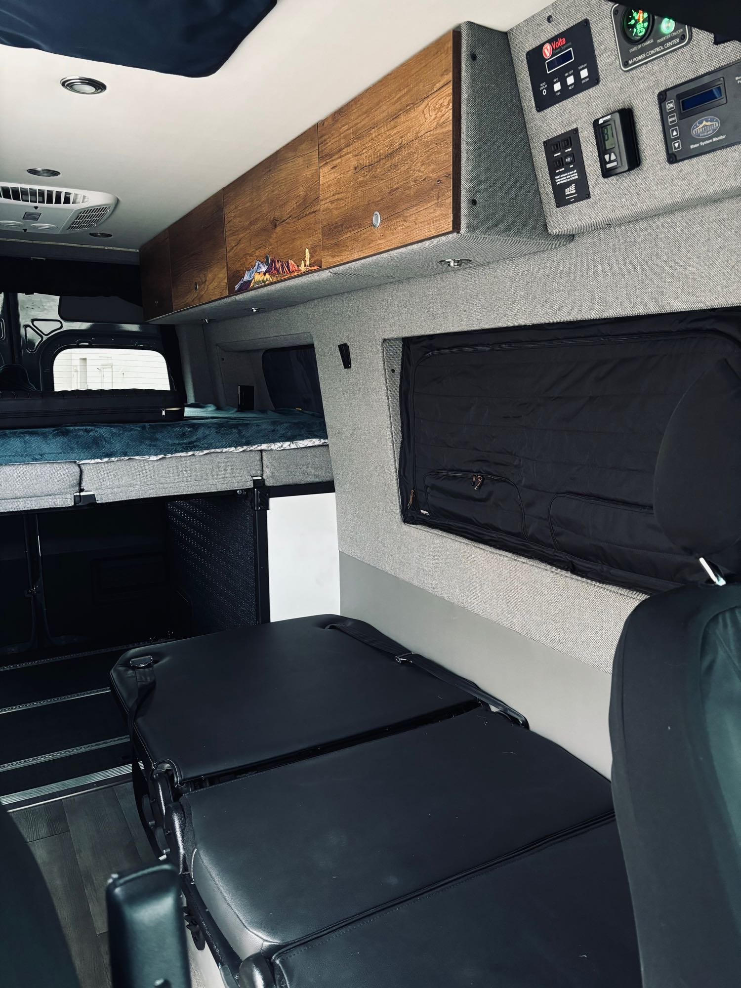 RV rental interior featuring a cozy bed, ample storage, and advanced power controls for a comfortable journey.. Storyteller Overland Stealth Storyteller Overland Class B 2021