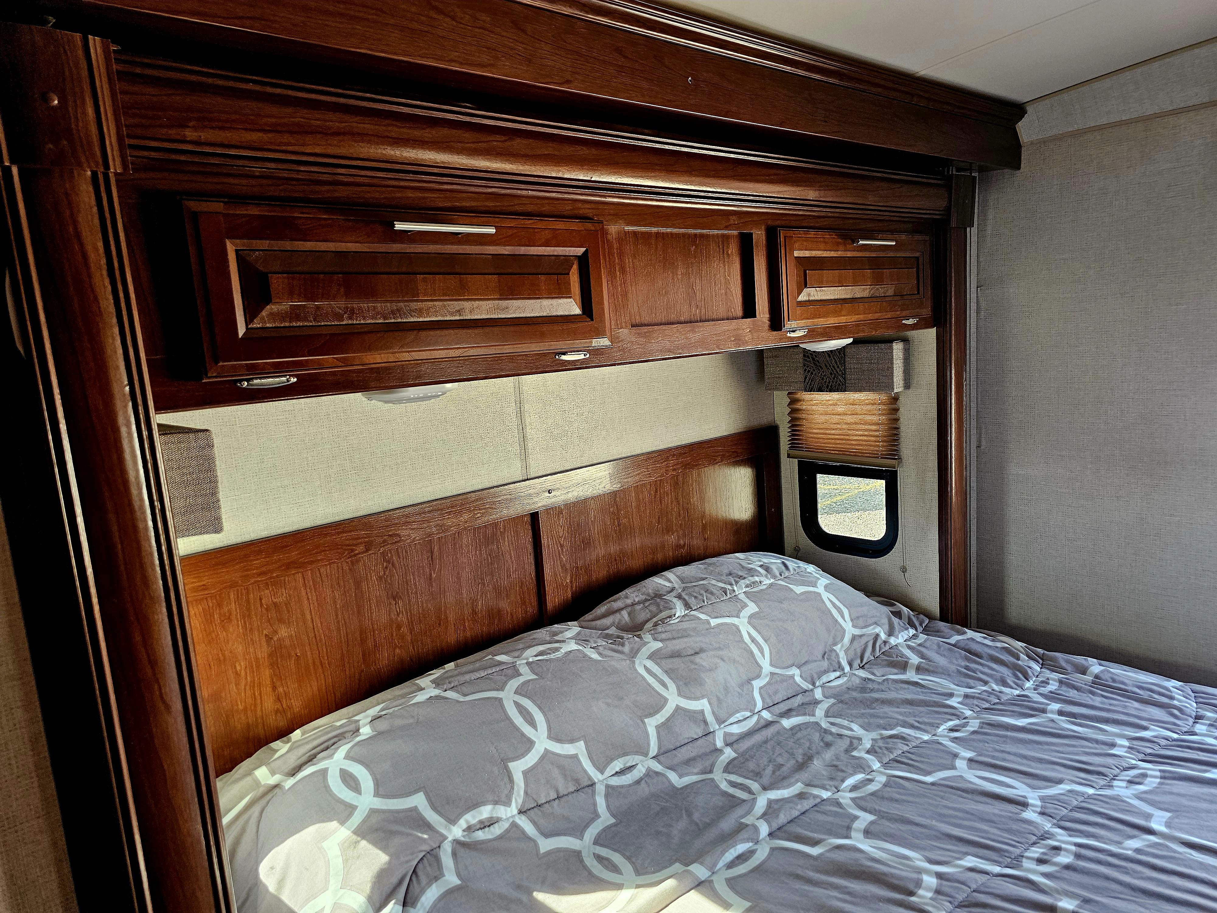 Cozy RV rental bedroom with warm wooden cabinets, a comfy bed, and a window with blinds, ready for your travels.. Forest River FR3 30DS 2017