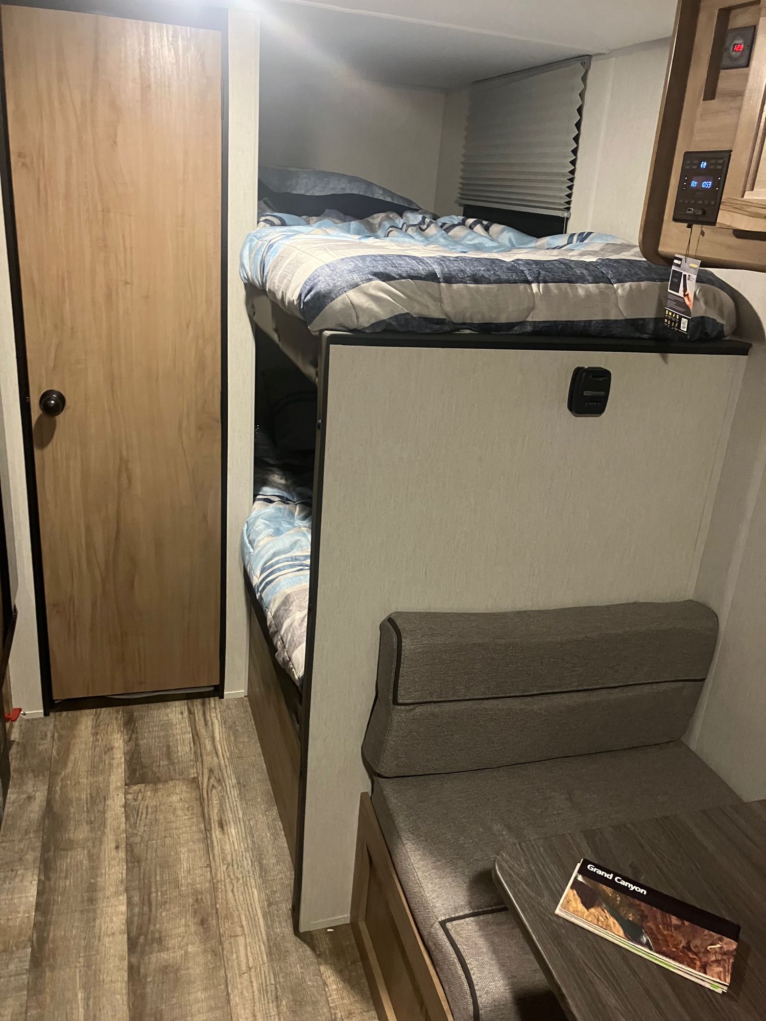 Compact RV rental interior featuring bunk beds with striped bedding, a dinette with a Grand Canyon brochure, and a wooden door.. Forest River Wolf Pup 16BHS BL 2024