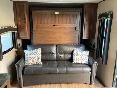 Inside an RV rental: a cozy living space with a comfy sofa and integrated Murphy bed for flexible sleeping.. Jayco Jay Flight 2016