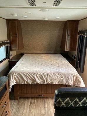 Inside an RV rental, this cozy bedroom features a comfortable bed, overhead storage, and window for your travels.. Jayco Jay Flight 2016