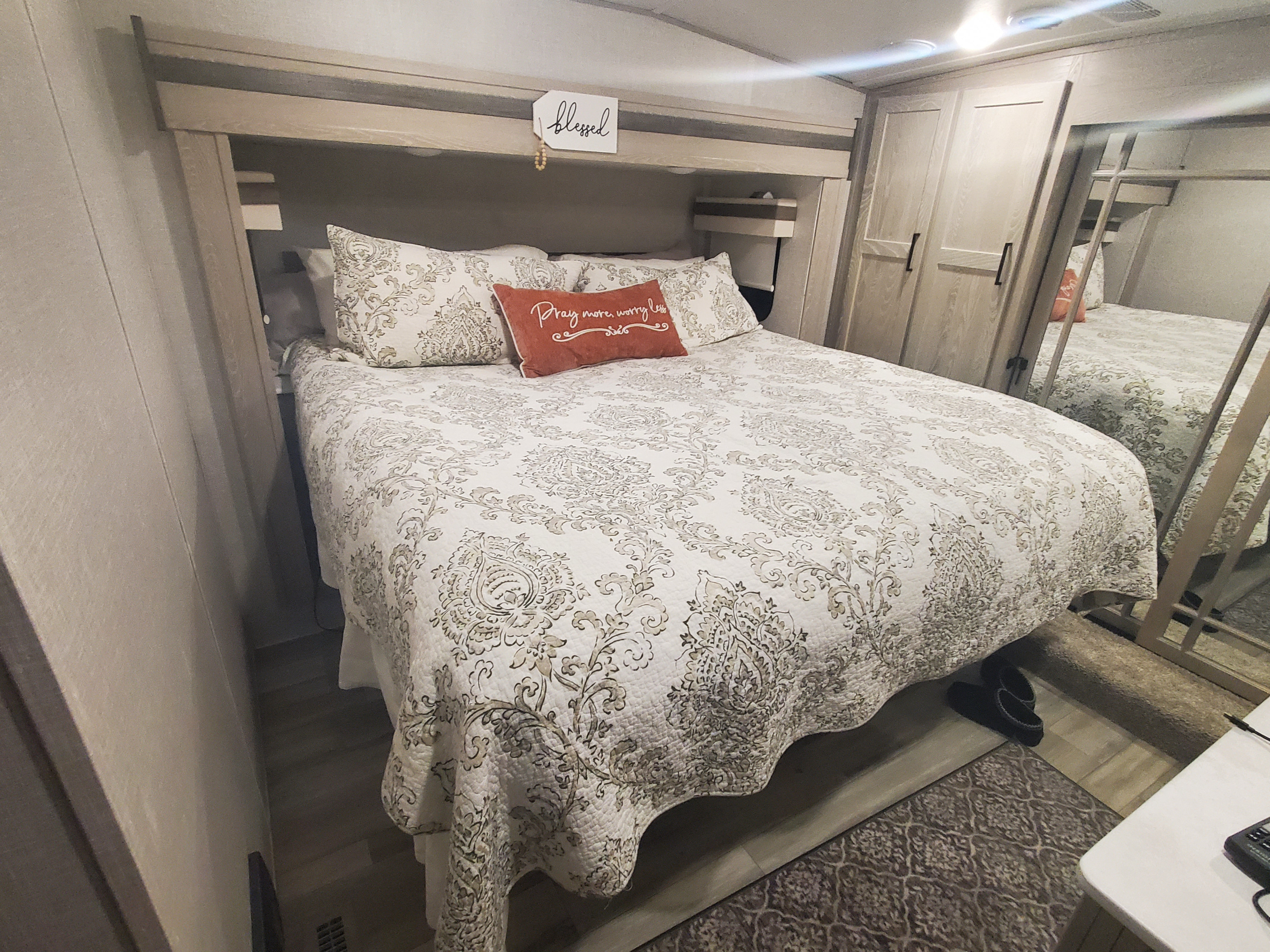 Cozy RV rental bedroom features a patterned bed, built-in storage, and mirrored wardrobe for comfortable travel.. Forest River Rockwood Ultra Lite 2022