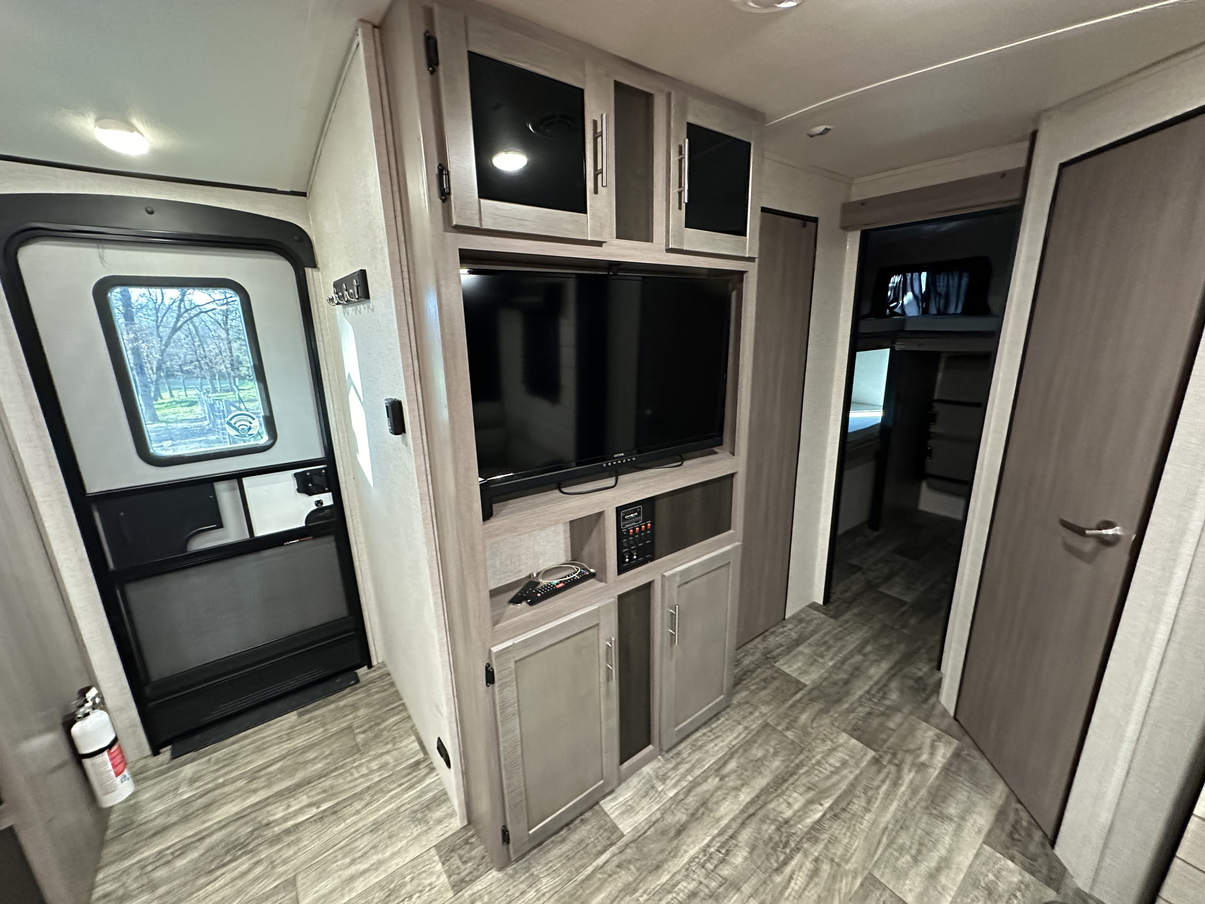 Step inside this RV rental! Modern interior with wood-look flooring, entertainment unit, main door, and bunk beds.. Crossroads RV Sunset Trail 2022