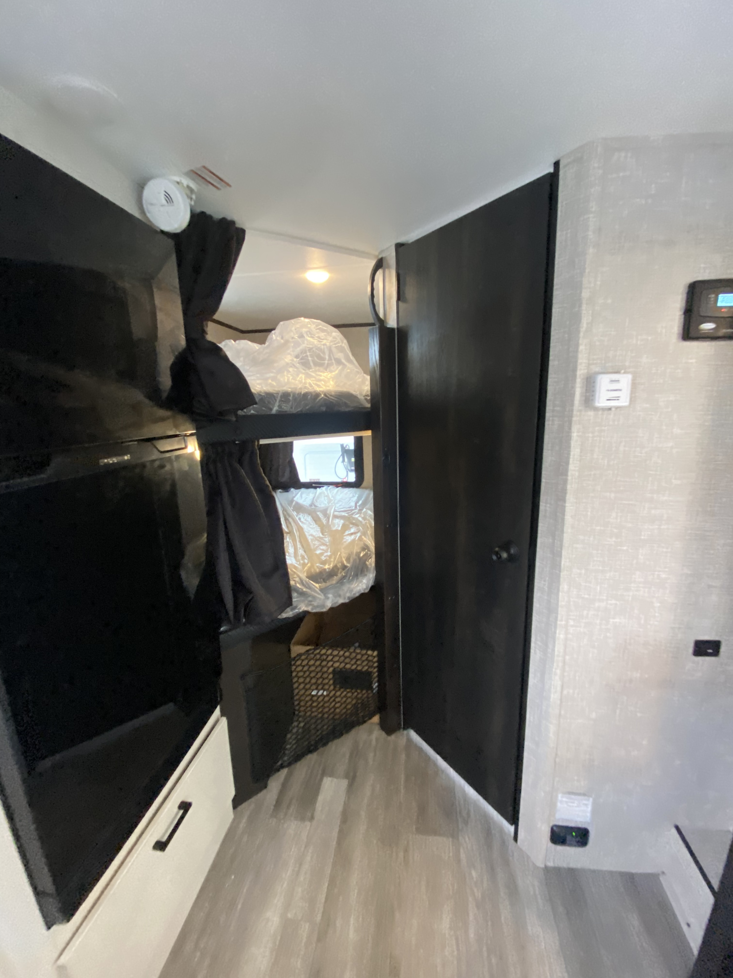 RV rental interior featuring stacked bunk beds with plastic-wrapped mattresses, a TV, and wall controls.. Jayco Jay Feather Micro 2023