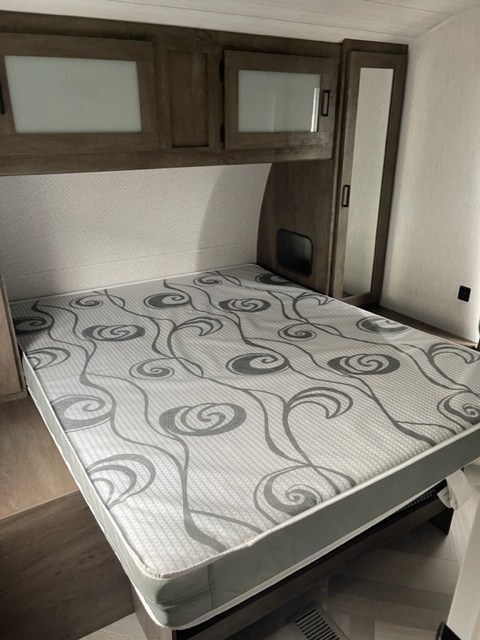 RV rental bedroom with bed, overhead cabinets, and mirrored closet. Perfect for a restful journey.. salem 29VBUD 2022