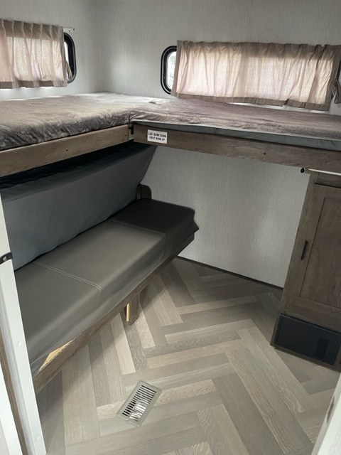 Cozy RV rental bunk beds with convertible sofa area, perfect for family adventures. Light herringbone flooring.. salem 29VBUD 2022