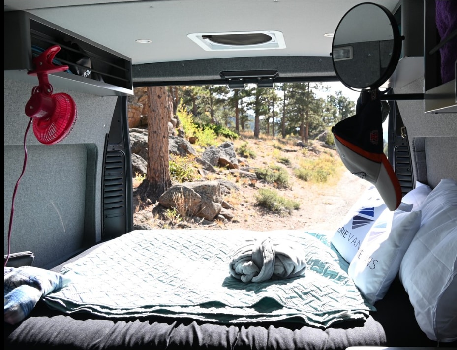 This cozy RV rental offers a bed with a view of a serene forest, ideal for your next camping adventure.. Dodge Sprinter Van 2021