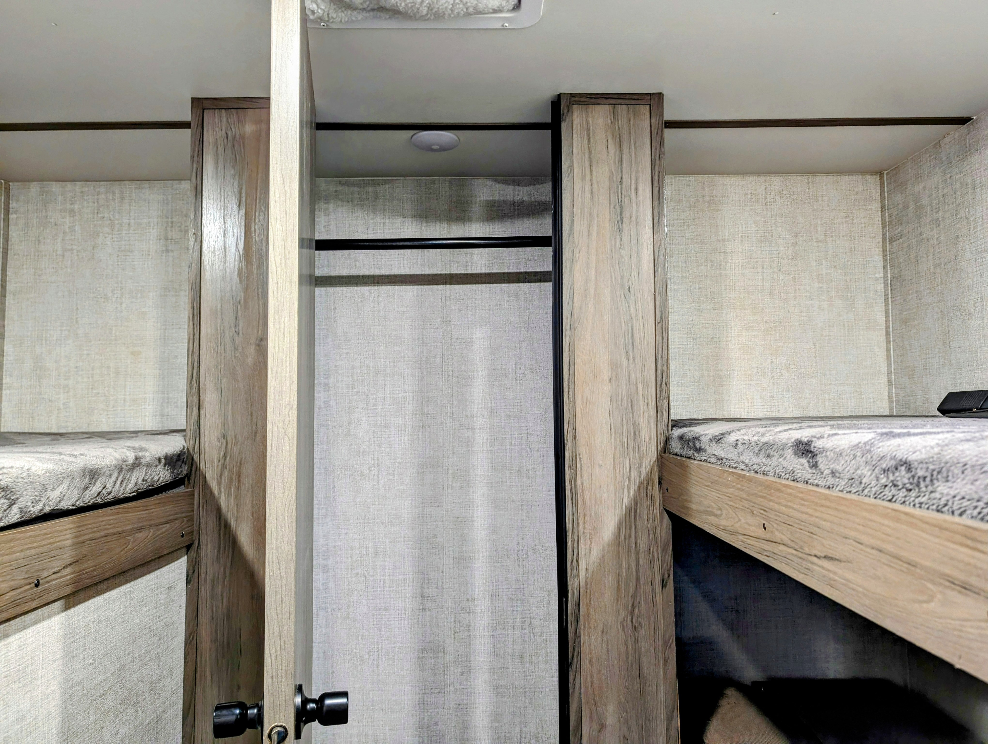 RV rental interior: cozy bunk beds flank a central closet with a hanging rod. Light wood and textured walls.. Gulf Stream Ameri-Lite 2022