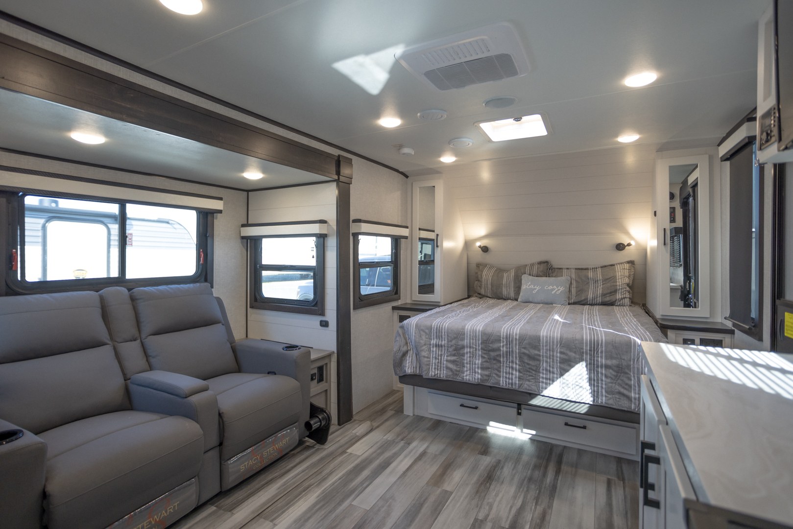 This rv rental showcases a modern, bright interior: recliners in the living space and a cozy bed in the bedroom area.. Jayco Jay Feather 2024
