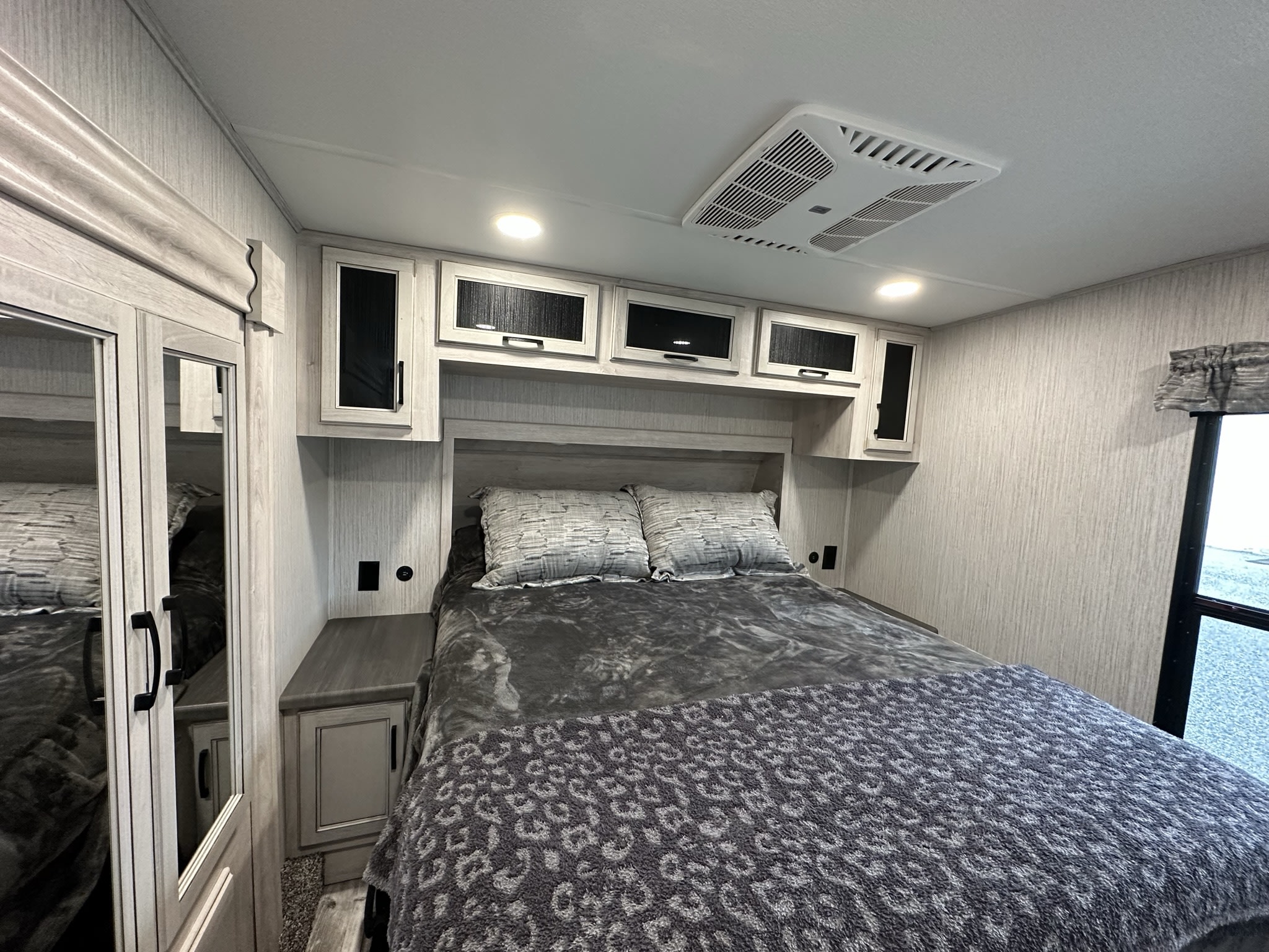 Bright RV rental bedroom: cozy bed, ample storage, and modern gray tones for comfortable travel.. Forest River Sierra 2022