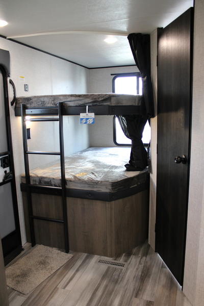 Inside an RV rental: a cozy bunk room with two beds, a ladder, window, and dark door, perfect for extra sleeping space.. Jayco Jay Flight 2024