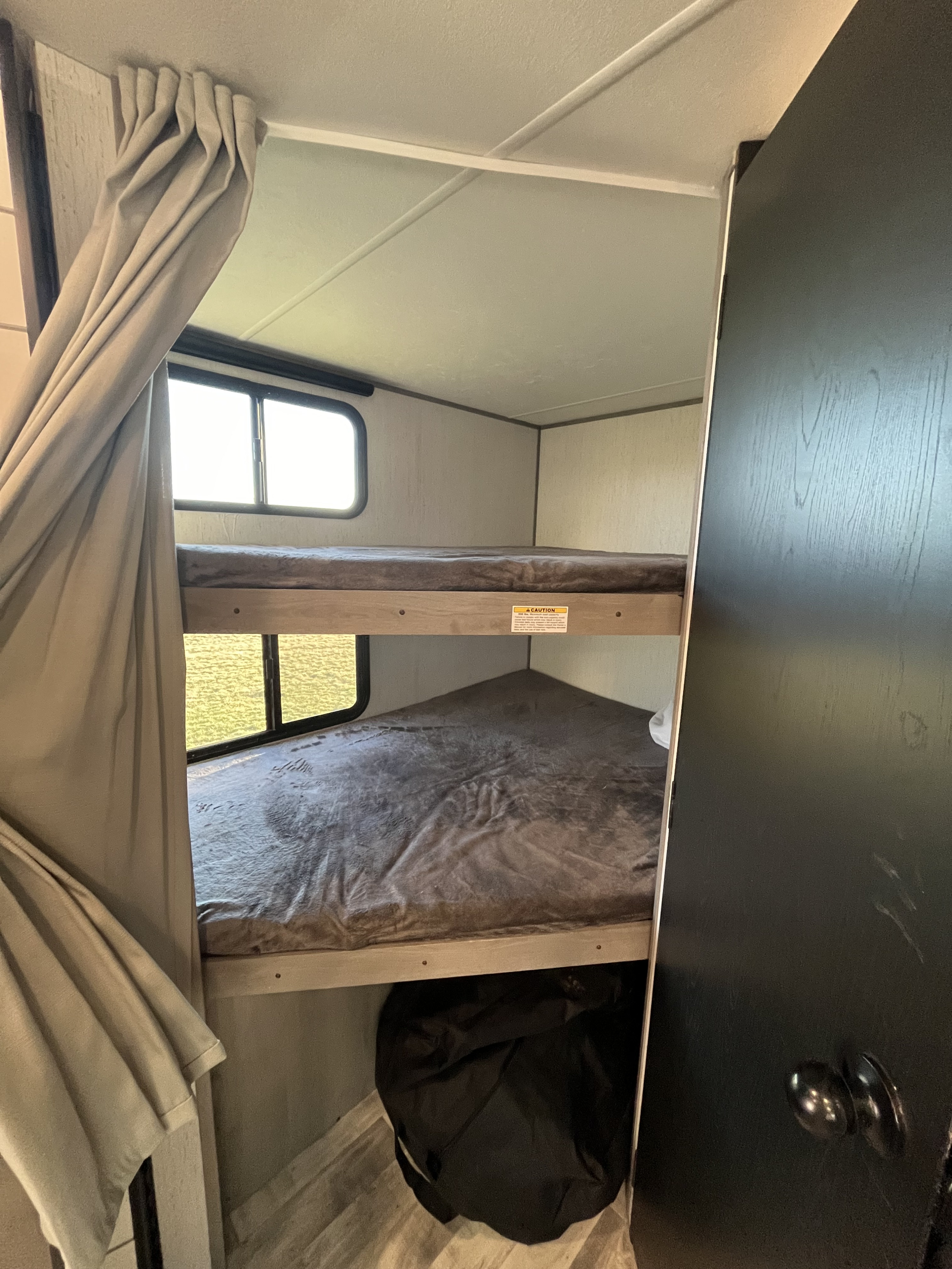 Inside an RV rental: two cozy bunk beds with windows and a privacy curtain, ideal for travelers.. Dutchmen Kodiak Bunk House 2019