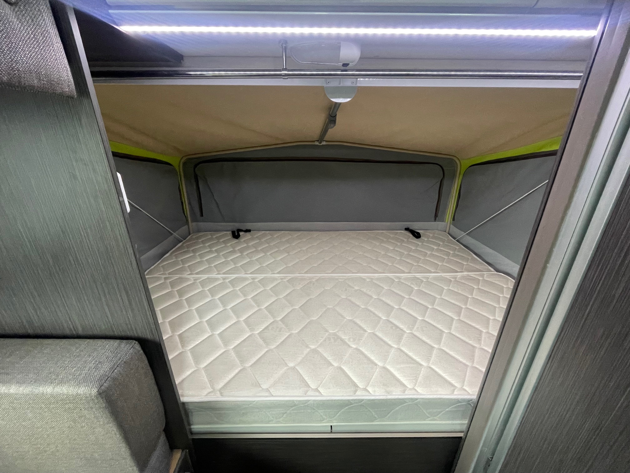 Inside an RV rental, a cozy pop-up bed with a comfortable mattress and bright LED lighting.. Jayco 17.56-2.OB.MY18 2018