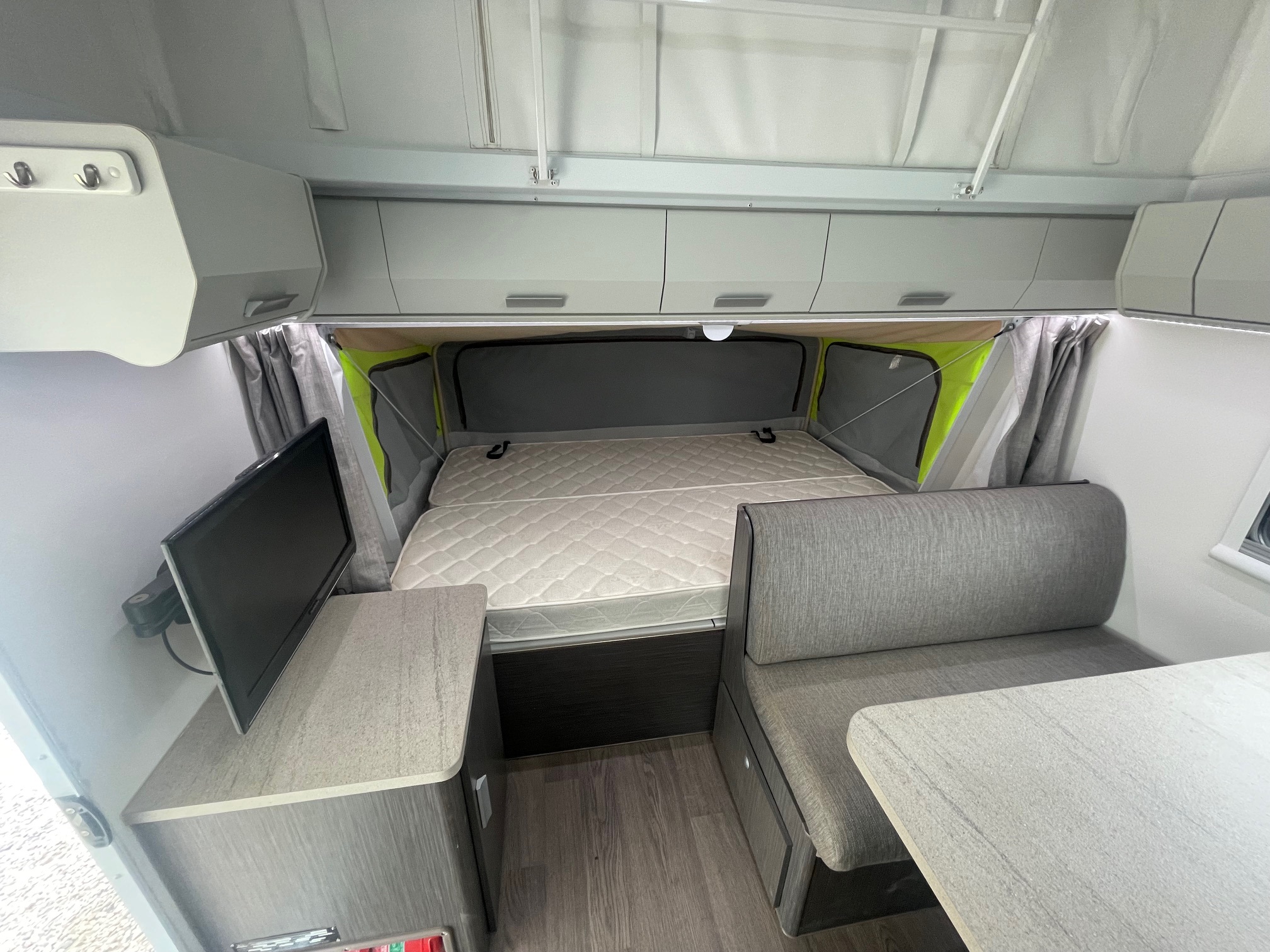 RV rental interior features a pop-top roof, comfy bed, dinette, and TV setup for your travels.. Jayco 17.56-2.OB.MY18 2018