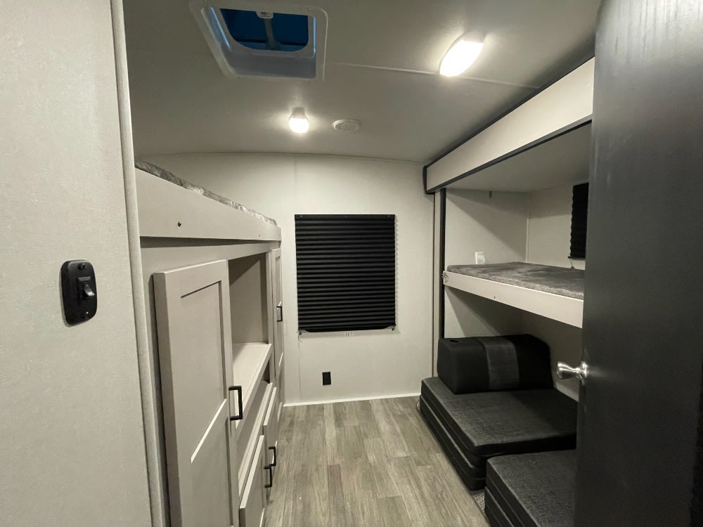 RV rental bunk room showcasing efficient design with two sets of bunk beds, storage cabinets, and convertible seating.. Heartland RVs Mallard 2023