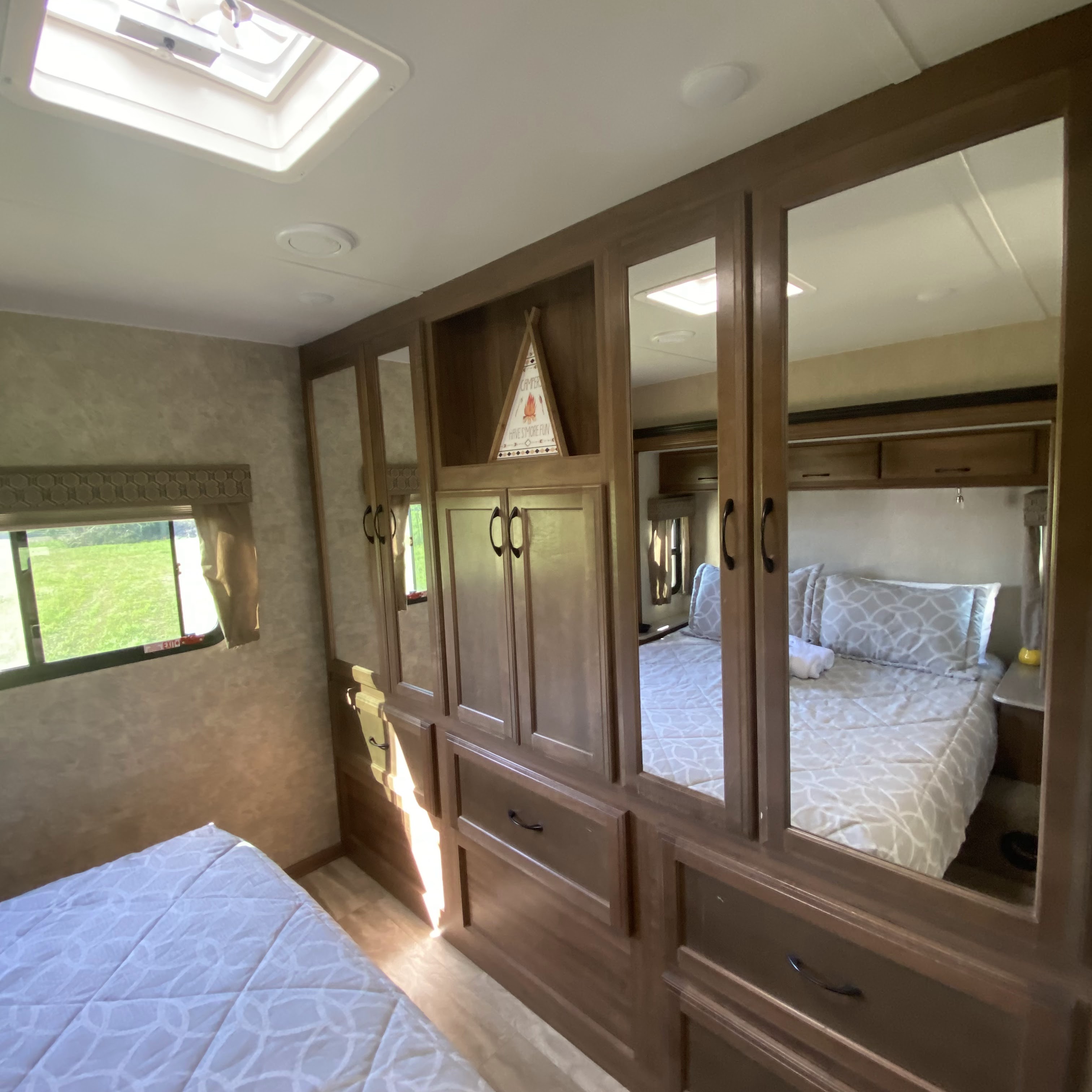 Inside an RV rental: a compact bedroom with mirrored wardrobe, comfortable bed, window, and ceiling skylight.. Gulf Stream Conquest 2019