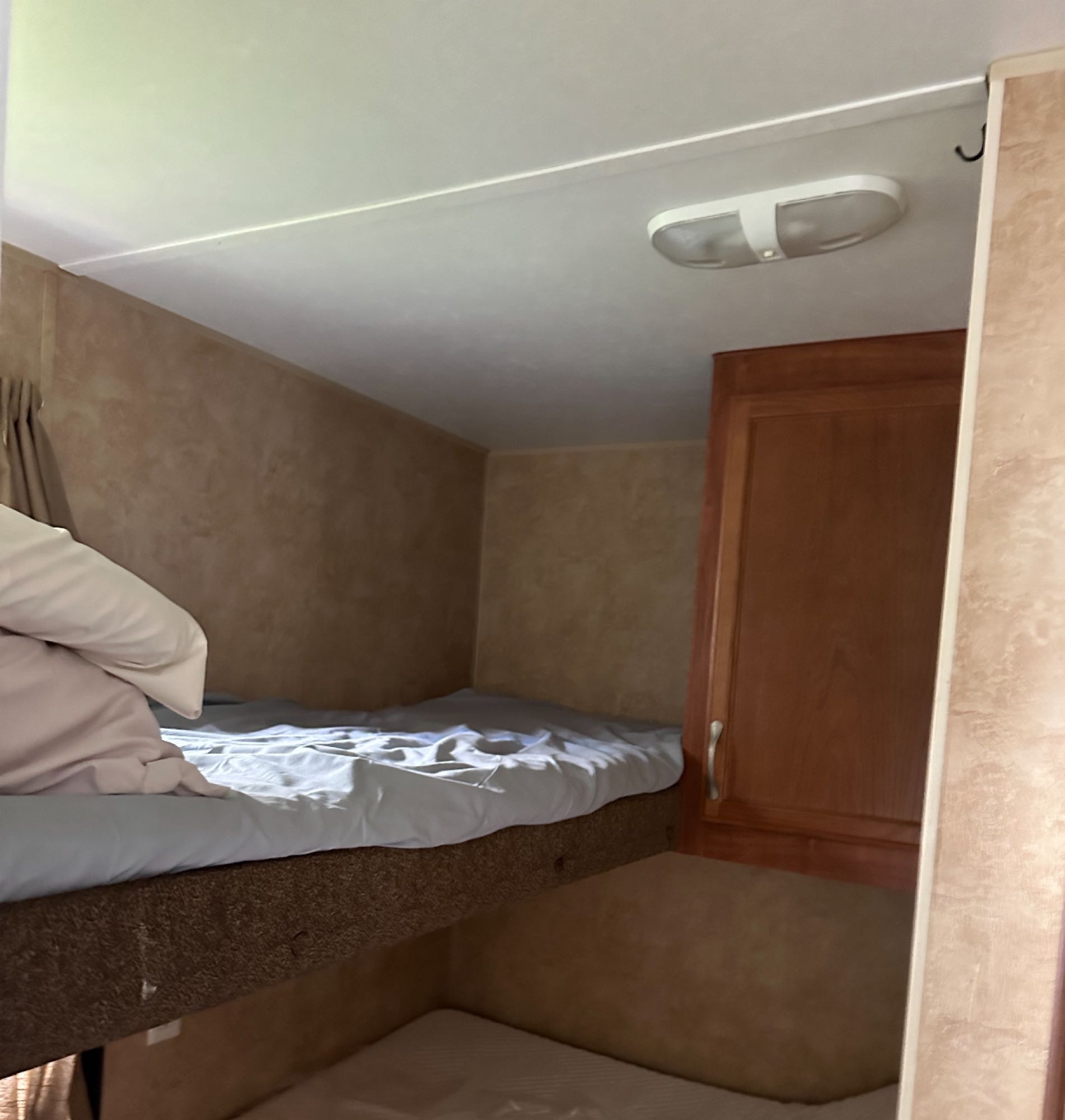RV rental: Interior view of bunk beds with white bedding, a wooden cabinet, and ceiling light. Compact sleeping space for travel.. Jayco Jay Flight 2011