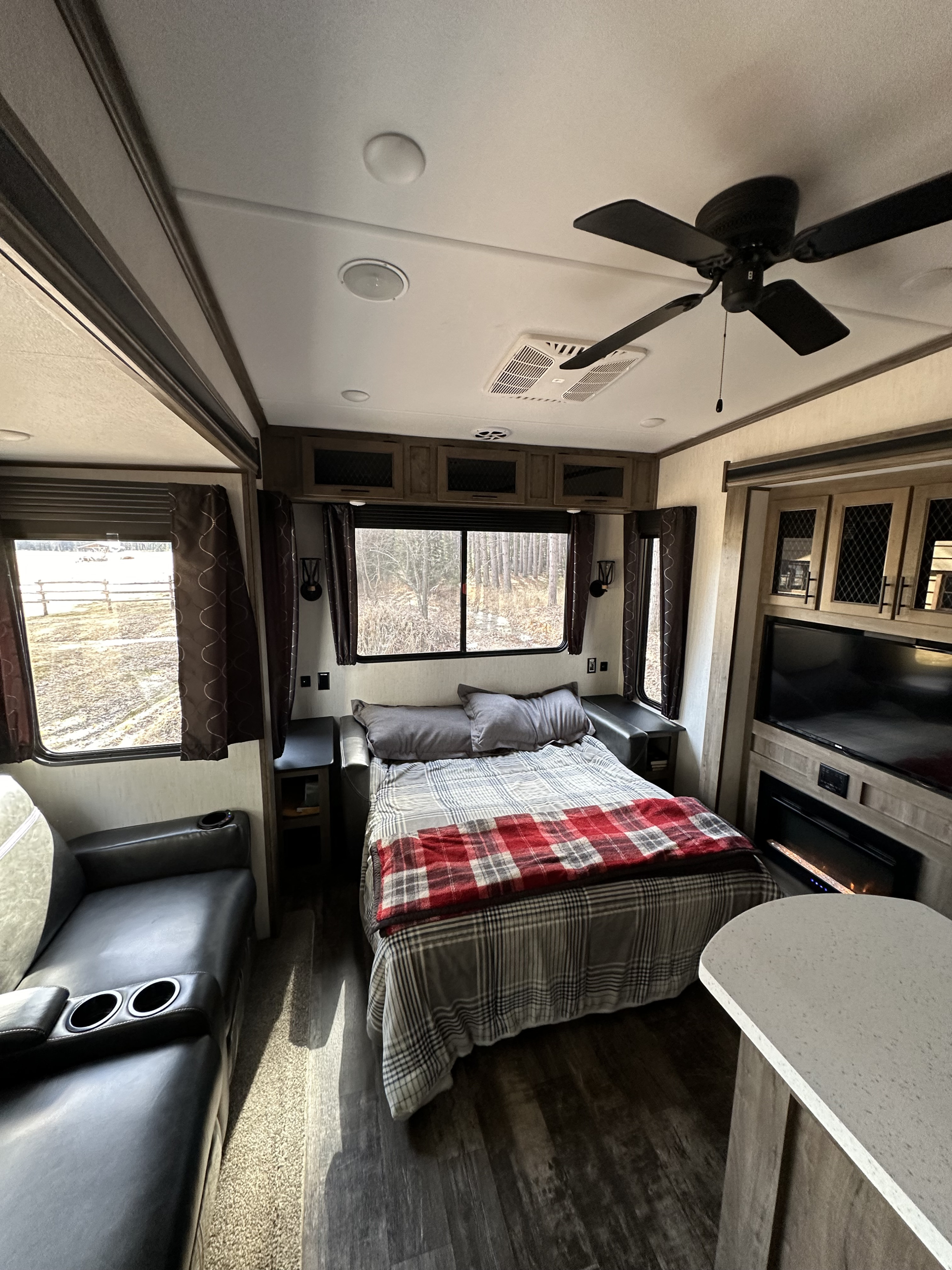 Inside an RV rental: a cozy bedroom/living area with a bed, TV, fireplace, and fan, ready for your adventure.. Forest River Sabre 2021