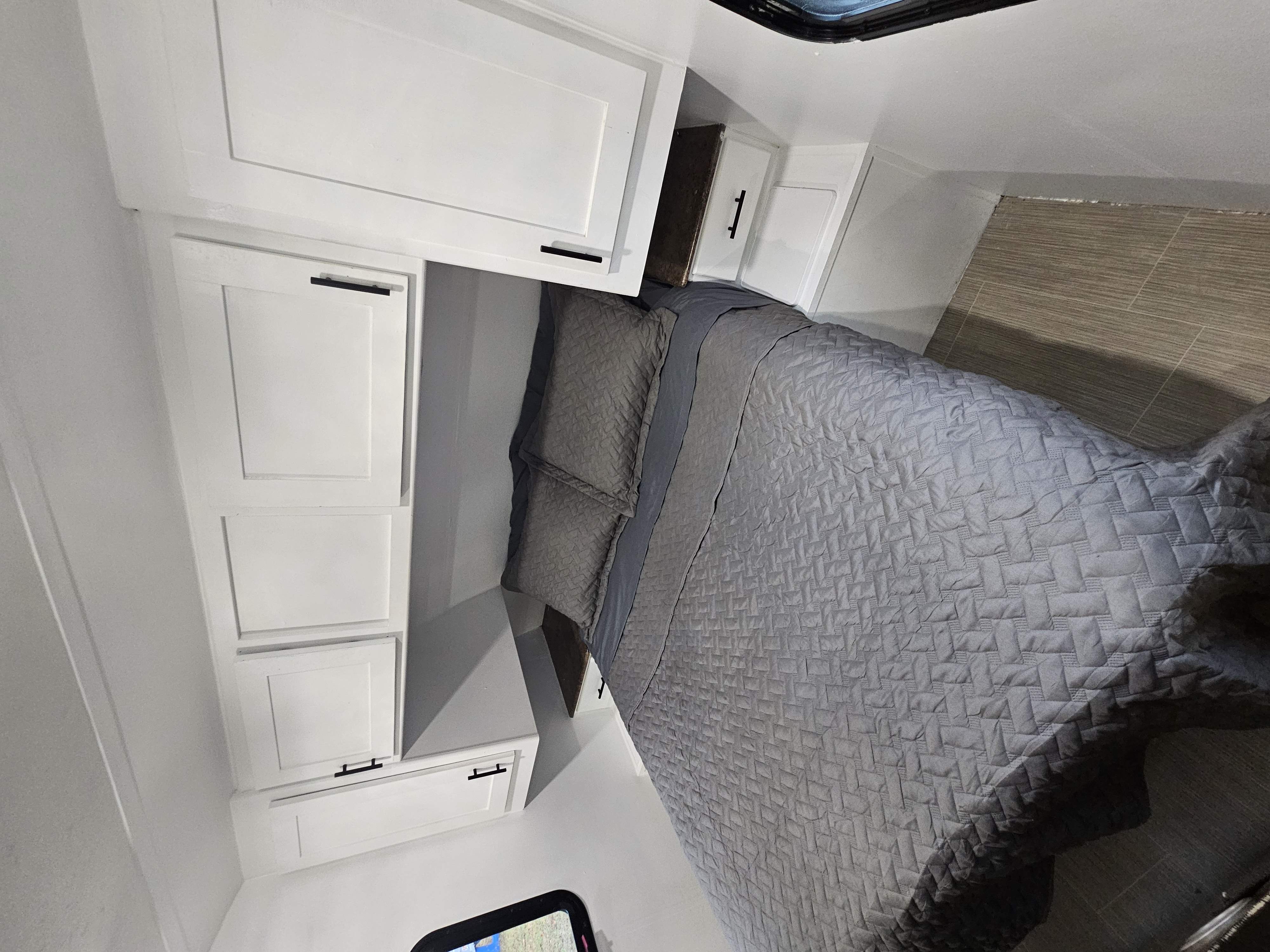 A bright and clean RV rental bedroom, featuring a comfy grey bed and modern white cabinetry.. Highland Ridge RV Open Range Ultra Lite 2017