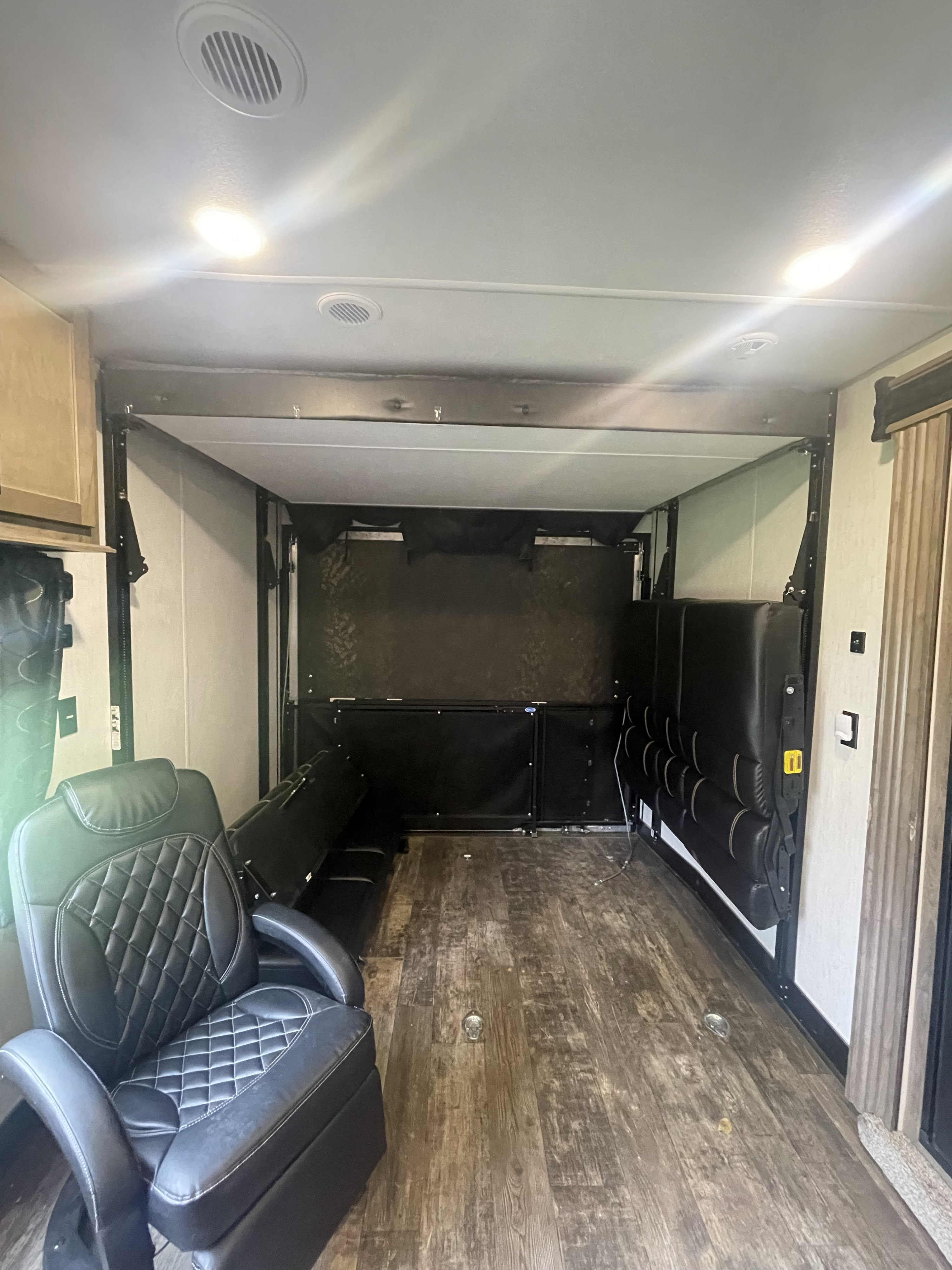 Spacious RV rental toy hauler interior featuring a comfortable recliner, versatile fold-up seating, and a large cargo area.. Forest River Cherokee Wolf Pack 2021