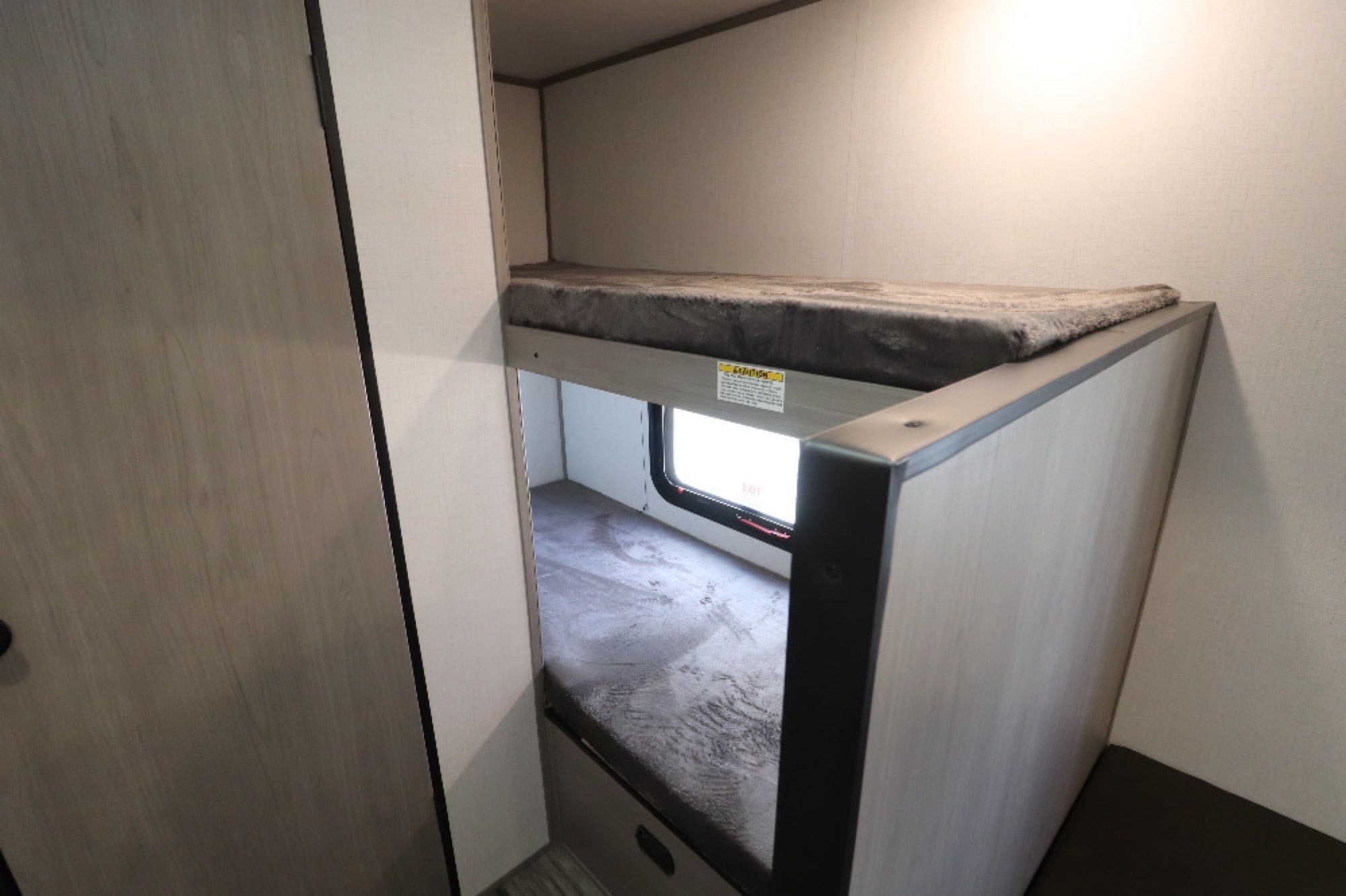 RV rental: Inside a modern travel trailer showing two bunk beds with grey mattresses and a small lower window.. Coleman LT17B 2024
