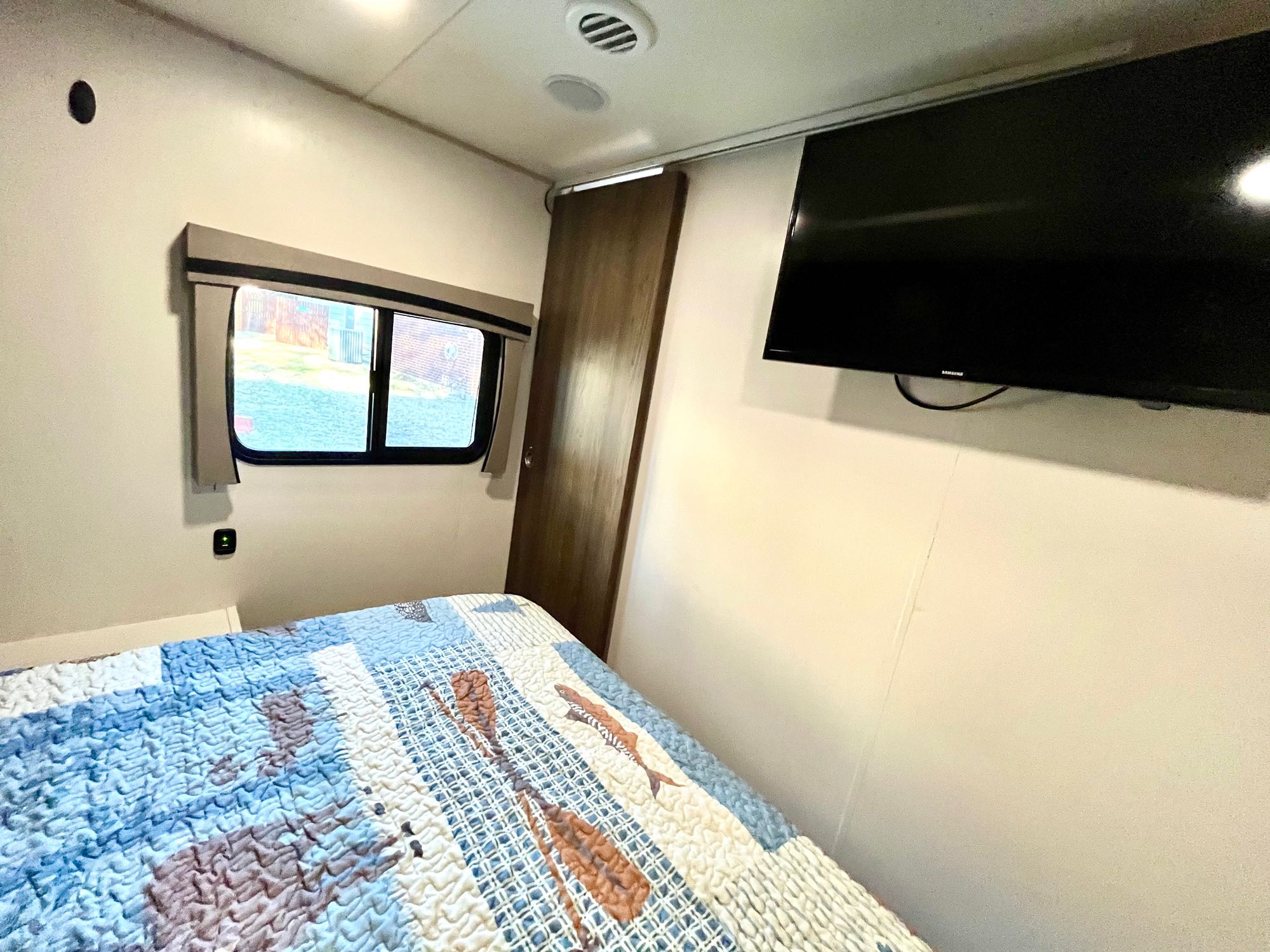 Cozy RV rental bedroom with a fish-themed bed, window, and wall-mounted TV. Your comfortable travel awaits.. Trail Wagon Chinook Dream D260BH 2021