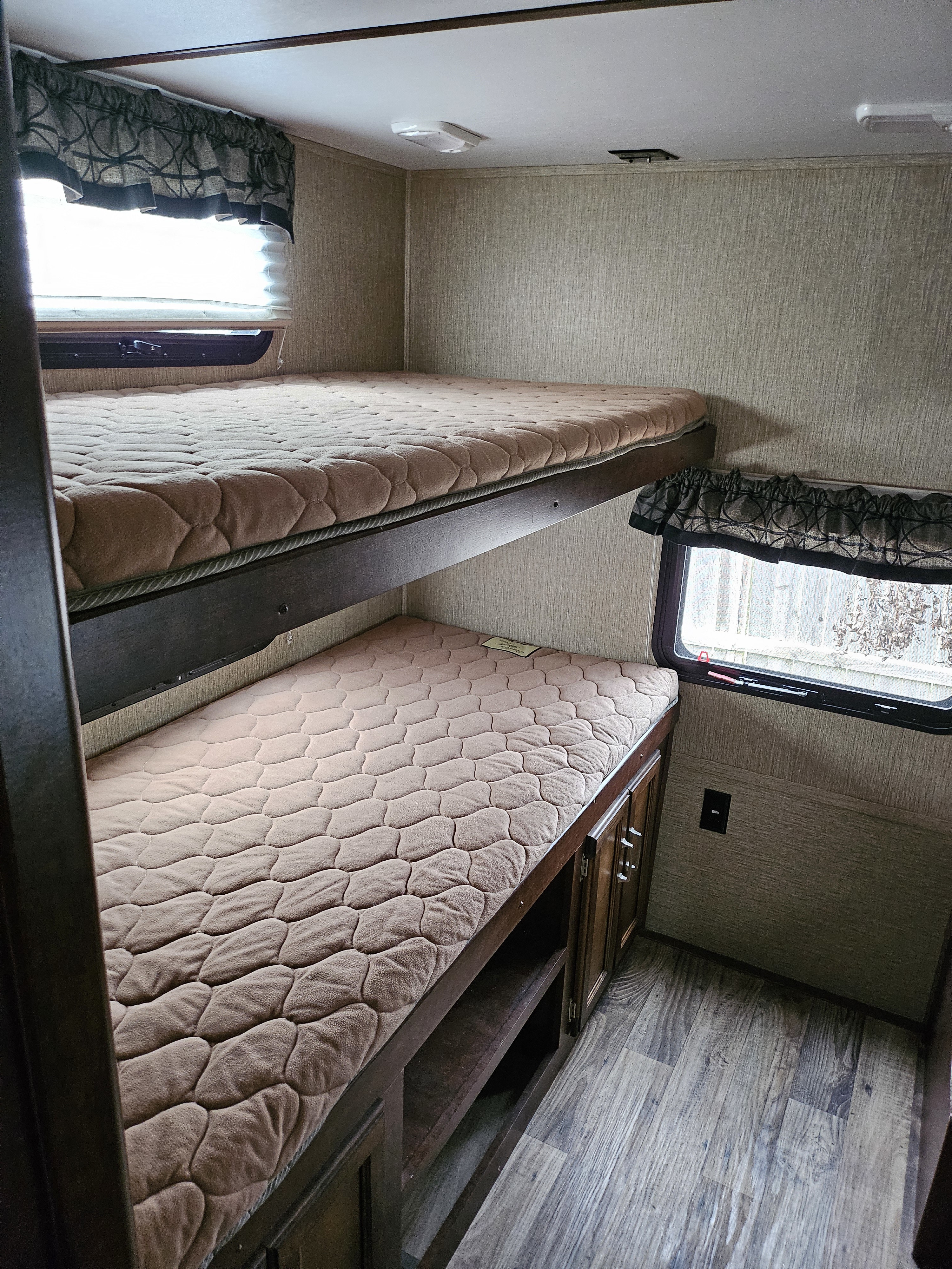 Cozy RV rental bunk beds. Compact sleeping area with two beds, windows, storage, and wood-look flooring.. Keystone Outback 2018