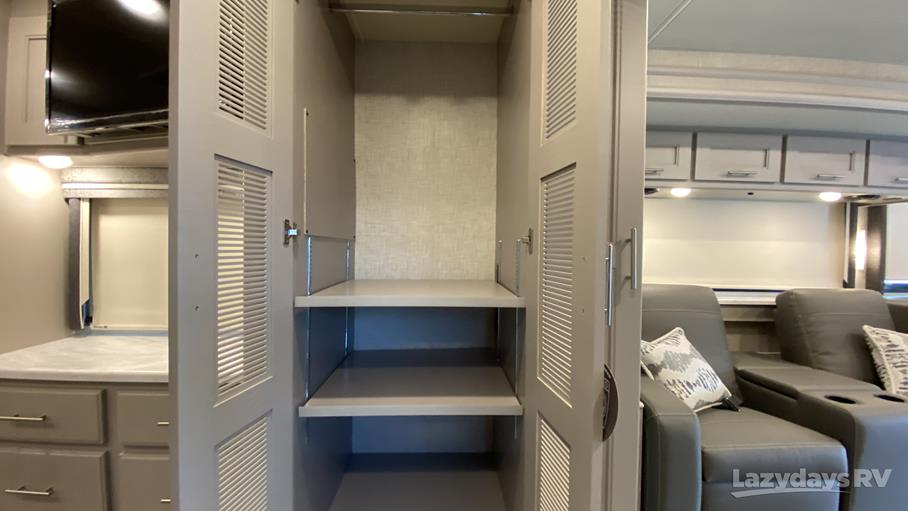 Inside an RV rental: versatile storage with shelves, a TV nook, and plush living area seating. Efficient interior design.. Thor Inception 2023