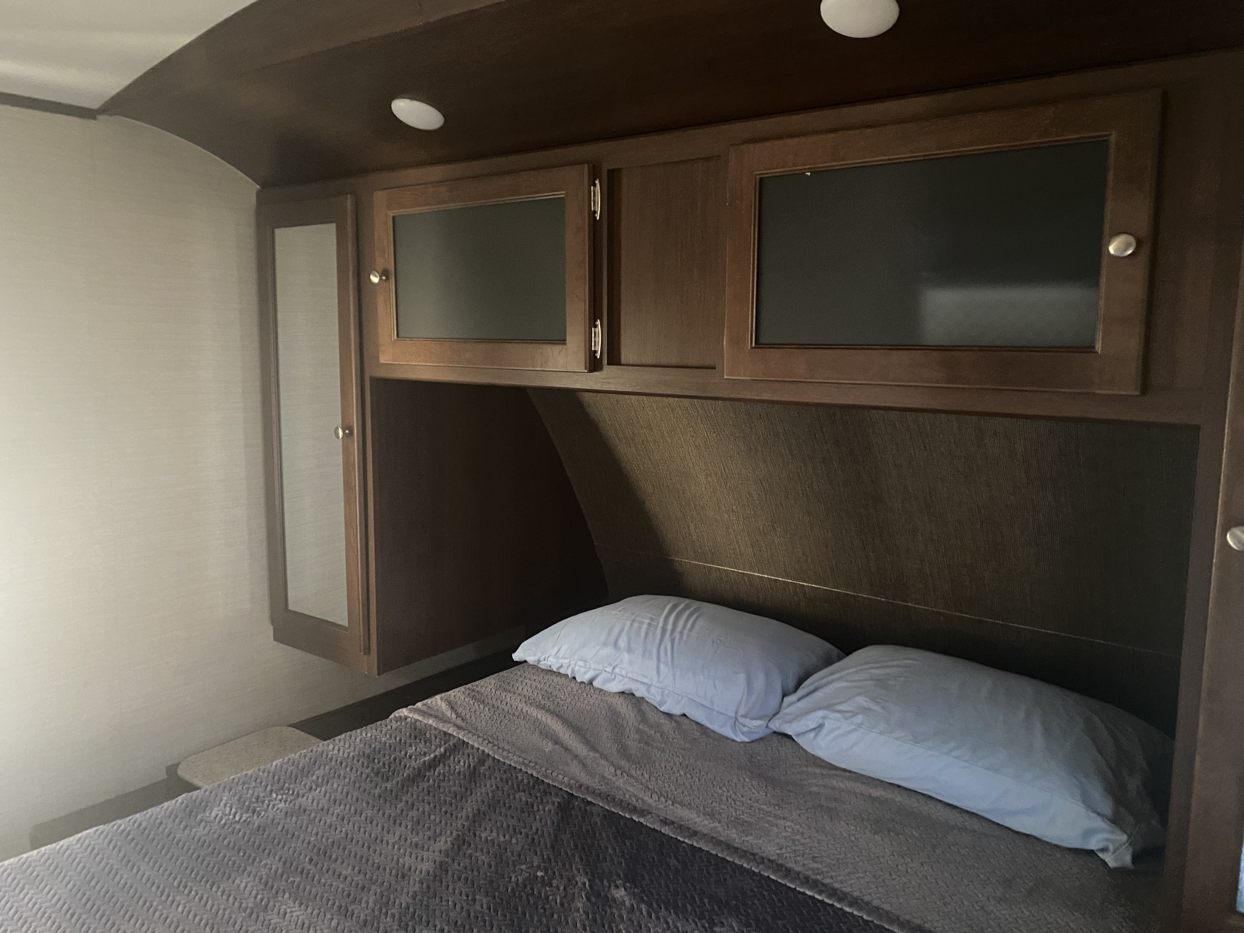 RV rental bedroom: features a comfortable bed with pillows, overhead cabinets, and a side closet.. Keystone RV Bullet Premier 2017