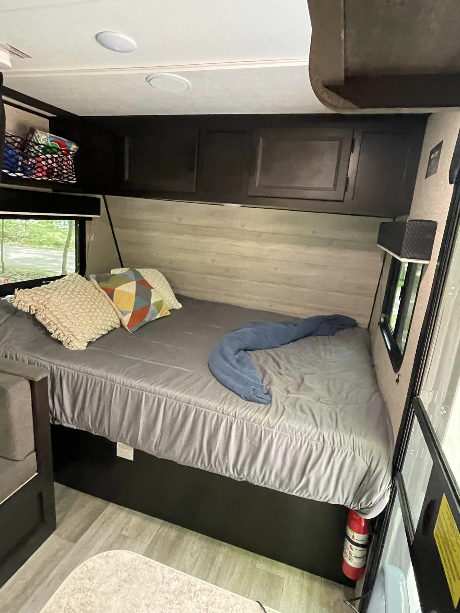 Cozy RV rental bedroom with gray bed, pillows, overhead cabinets, and windows. Perfect for camping adventures.. Jayco Jay Flight SLX 174BH 2022