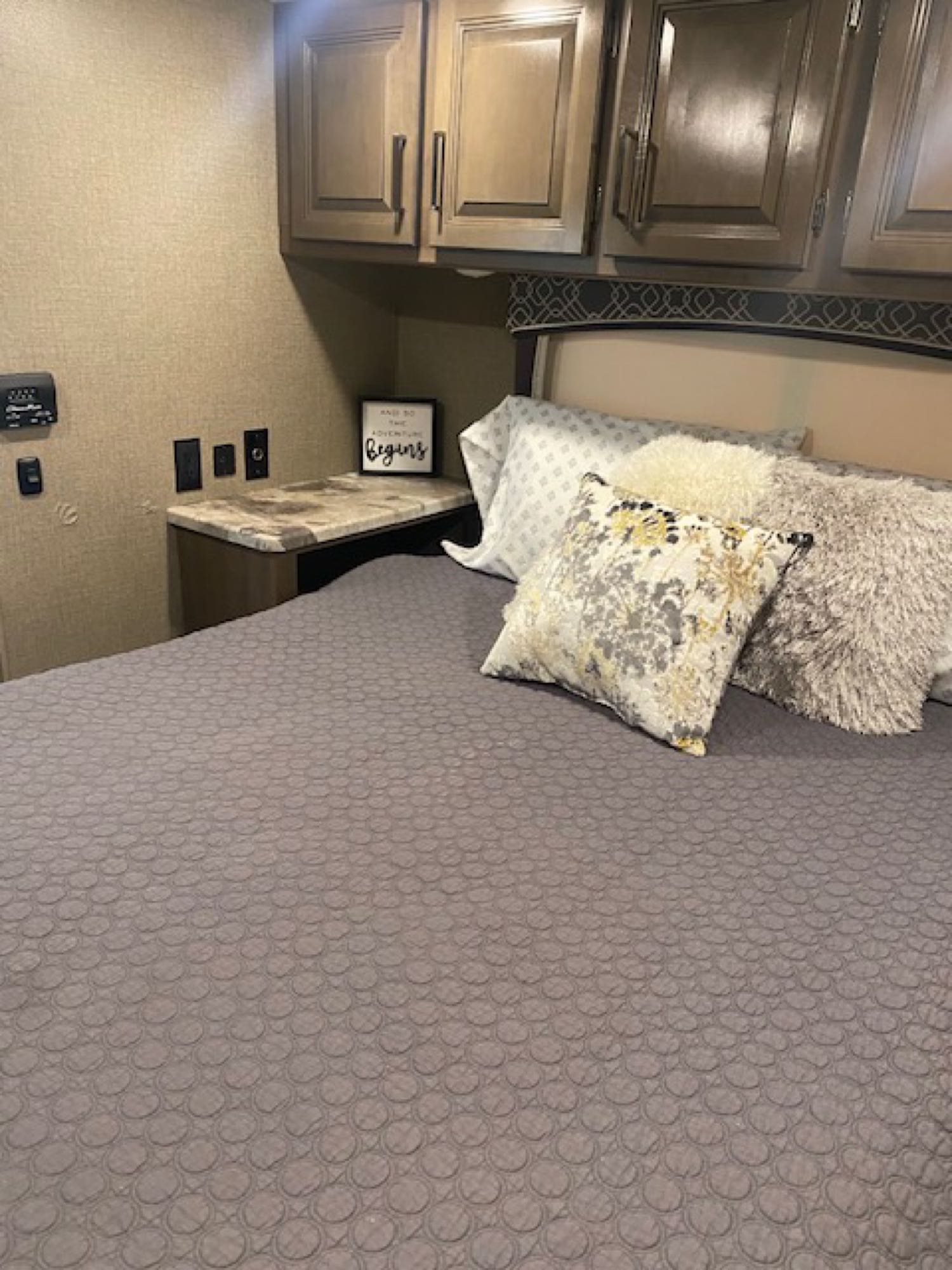 Cozy RV rental bedroom with a comfortable bed, overhead storage, and a hopeful 'Begins' sign on the nightstand.. Thor Chateau 2021