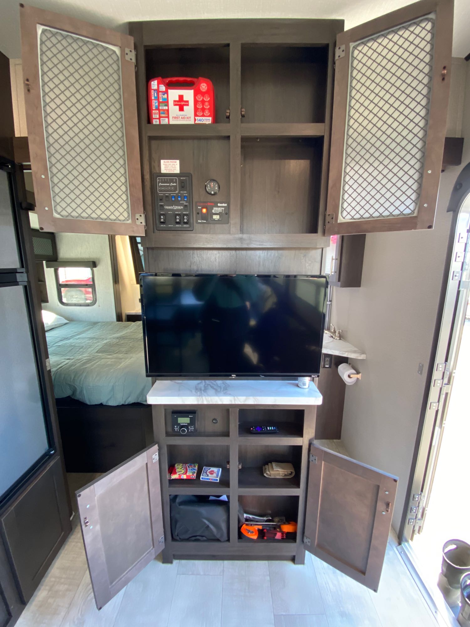 Tour this RV rental's cozy interior, featuring a TV, bed, fridge, and accessible storage with controls and a first aid kit.. Grand Design Momentum 2021
