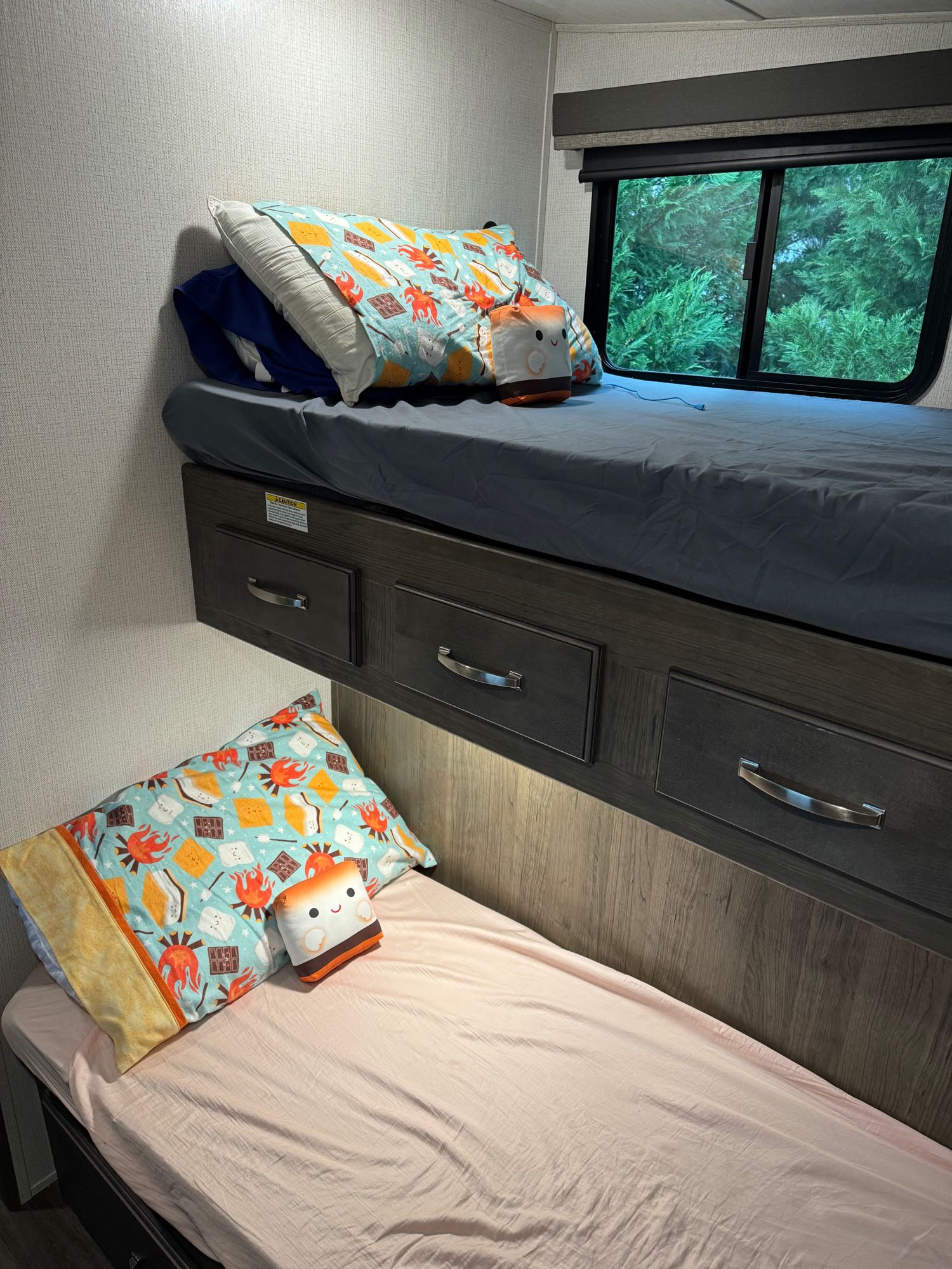 Inside an rv rental, cozy bunk beds with s'mores pillows, storage drawers, and a window view. Ideal family sleep space.. Keystone RV Cougar 2023