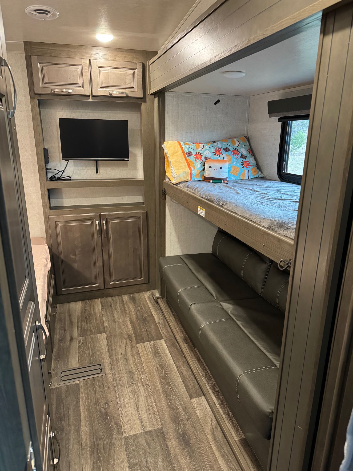 This RV rental interior features bunk beds, a lower sofa/bed, TV, and ample storage, ideal for travel comfort.. Keystone RV Cougar 2023