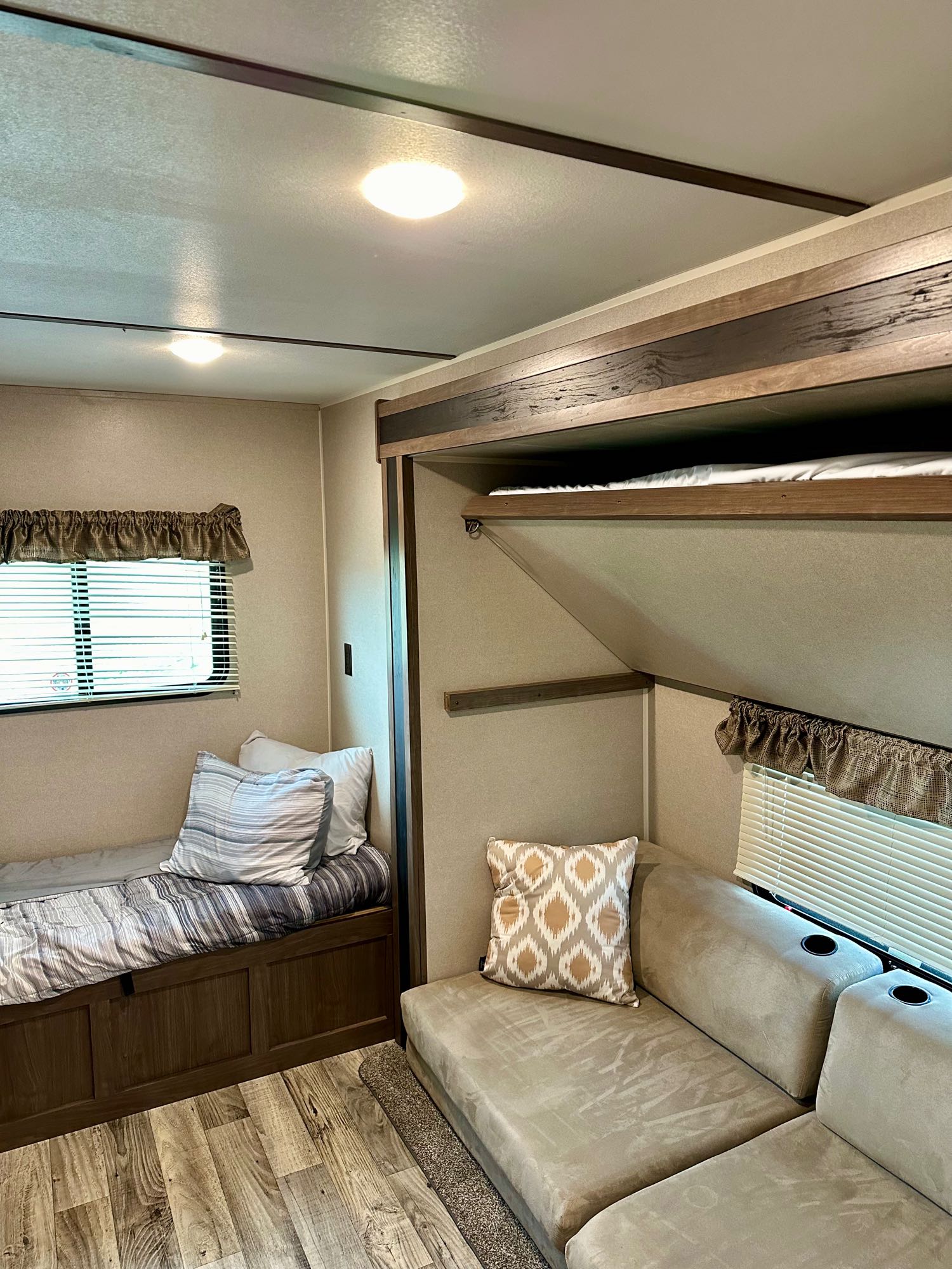 Spacious RV rental interior with a bed, comfortable sofa with cup holders, and an upper bunk, ideal for family travel.. Keystone RV Hideout LHS 2020