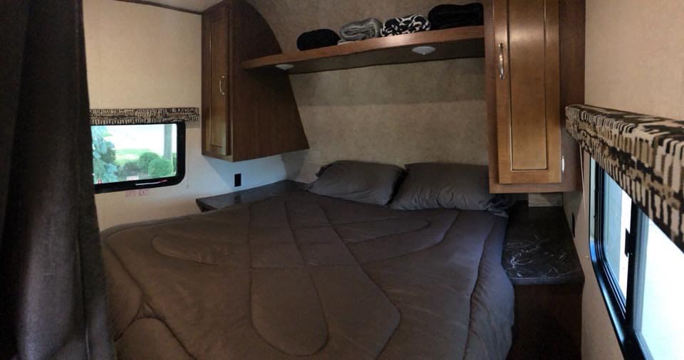 This RV rental bedroom features a comfortable bed, overhead storage, and windows with outdoor views.. Jayco Jay Flight SLX 2017