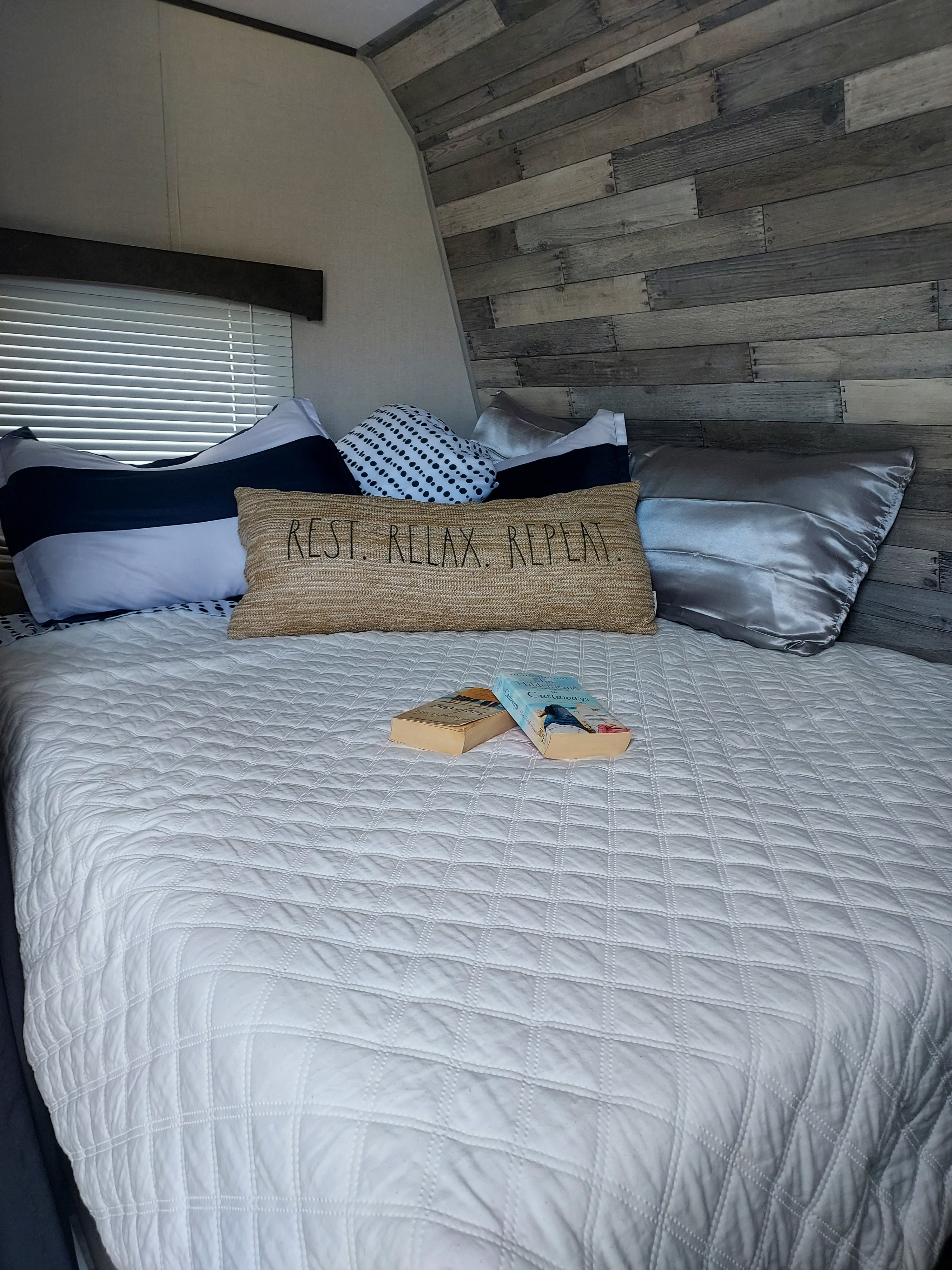Discover the comfortable RV rental bedroom, featuring quilted bedding and a 'REST. RELAX. REPEAT.' pillow.. Crossroads RV Zinger Lite 2022