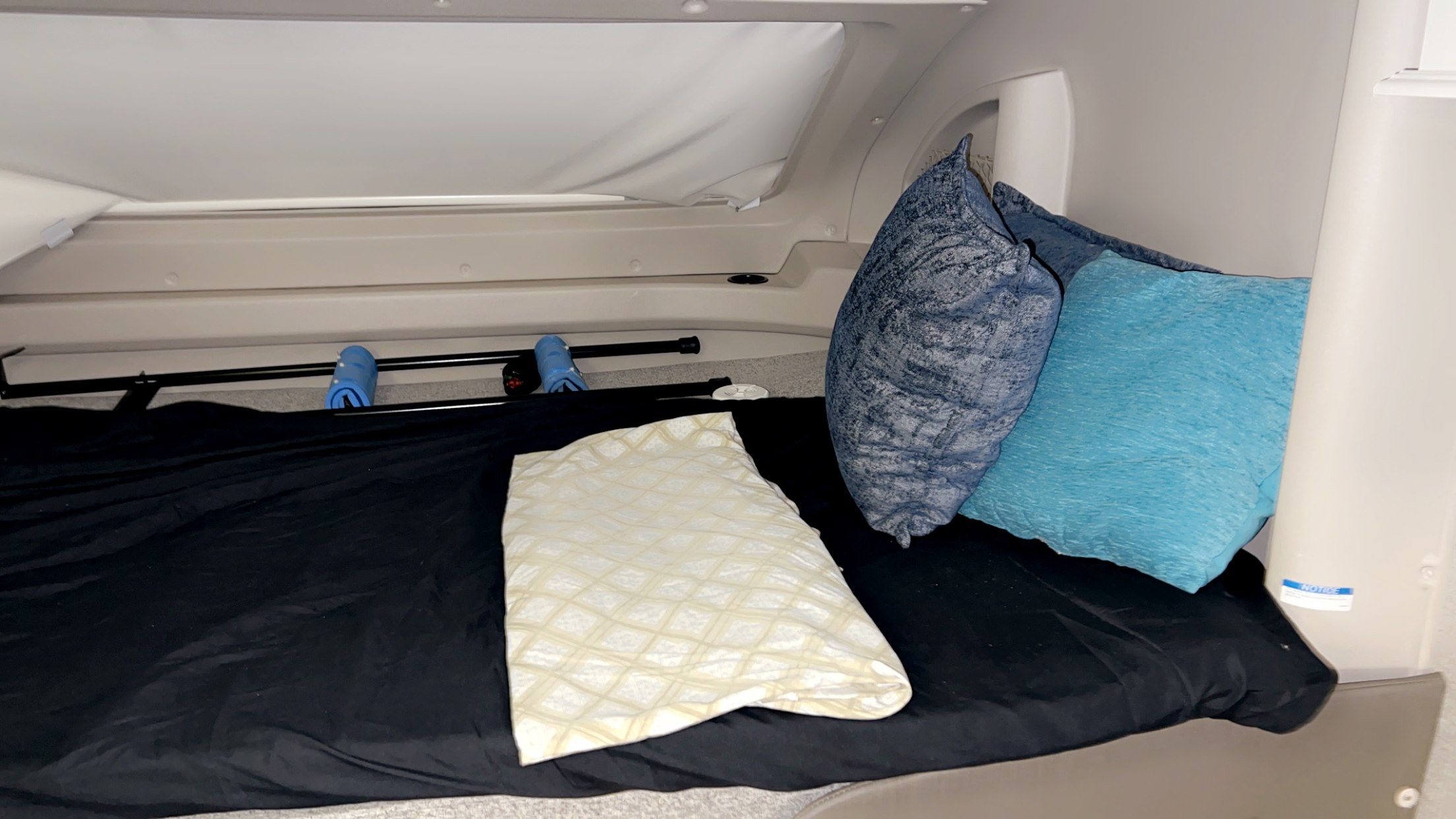 Comfortable sleeping area in an RV rental, featuring a black bed, three pillows, and overhead storage.. Entegra Coach Odyssey 2021