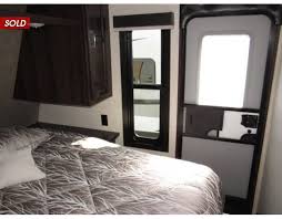 RV rental bedroom interior: a compact space with a patterned bed, window, & entry door on the right.. Jayco Jay Flight SLX 2020