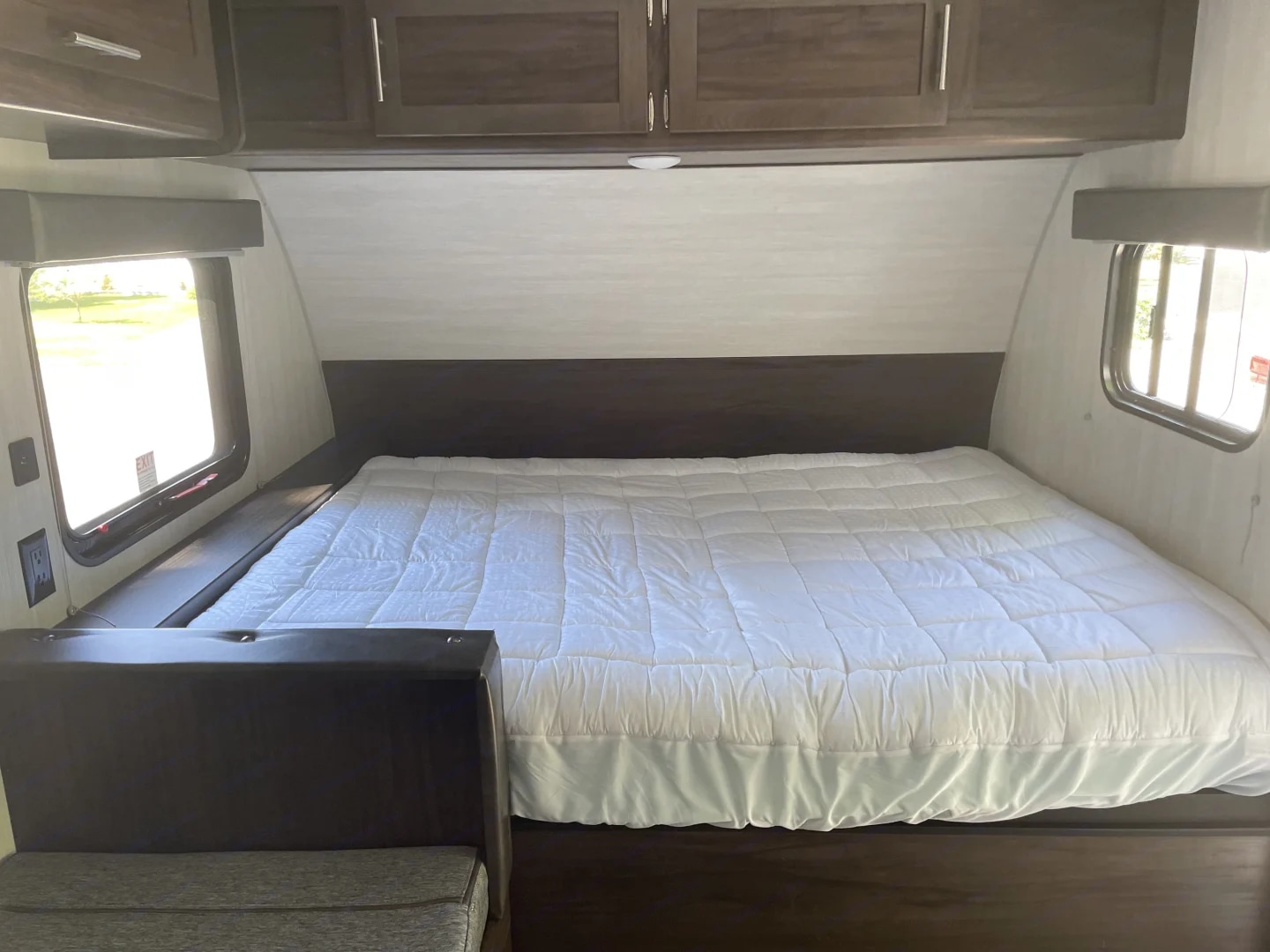 Cozy RV rental bedroom features a large bed, side windows, & overhead cabinets. Ideal for a camper trip.. Forest River Cherokee Wolf Pup 2019