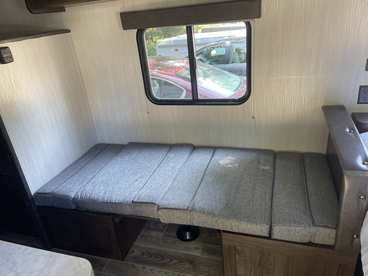 RV rental interior: Grey textured cushions on a convertible bench for seating/sleeping, with an outside view.. Forest River Cherokee Wolf Pup 2019