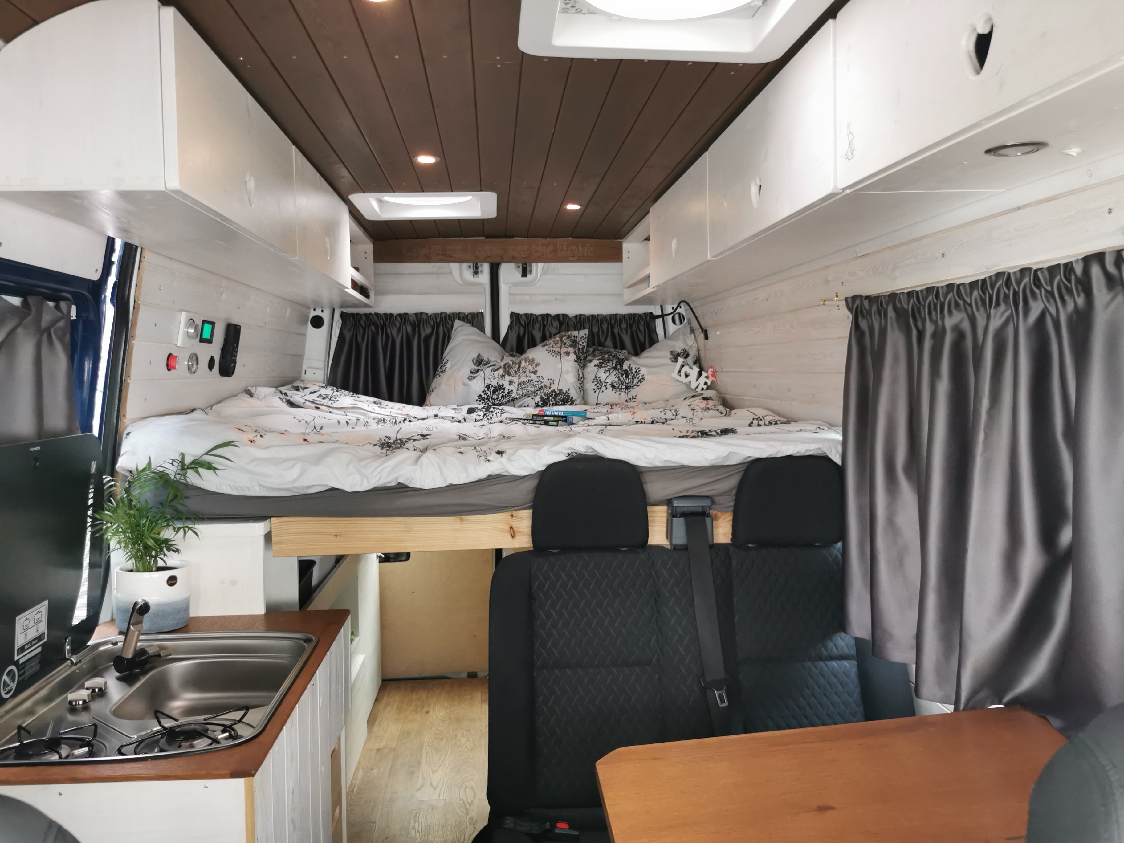 RV rental: Inside a modern camper van with a cozy bed, compact kitchen (sink/stove), and passenger seating.. Leisure Travel Vans Leisure Travel Vans Class B 2006