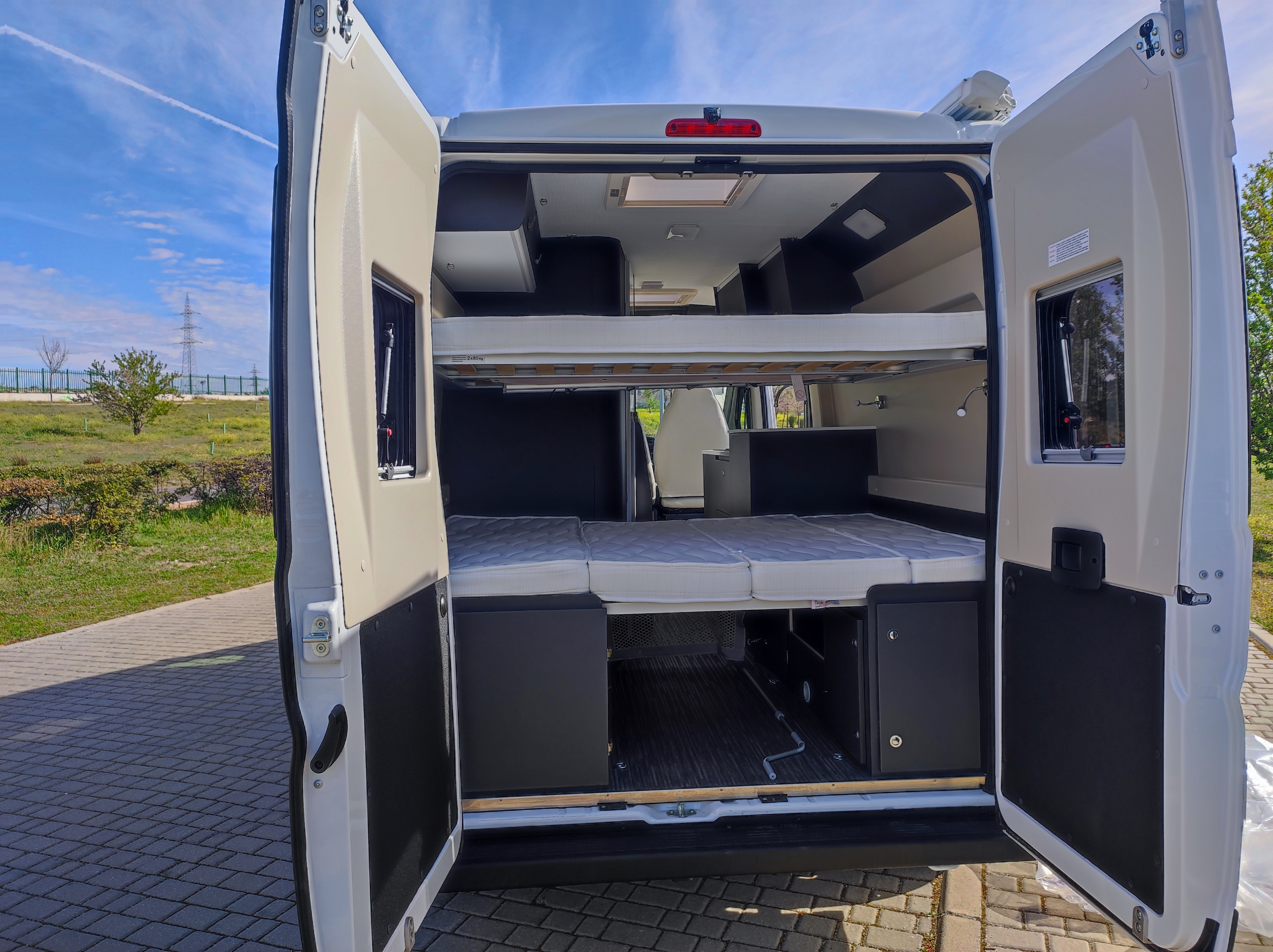 Rear view of an RV rental's interior, showcasing spacious bunk beds and storage. Perfect for camper van adventures.. McLouis Menfys Van 3 Maxi 2024