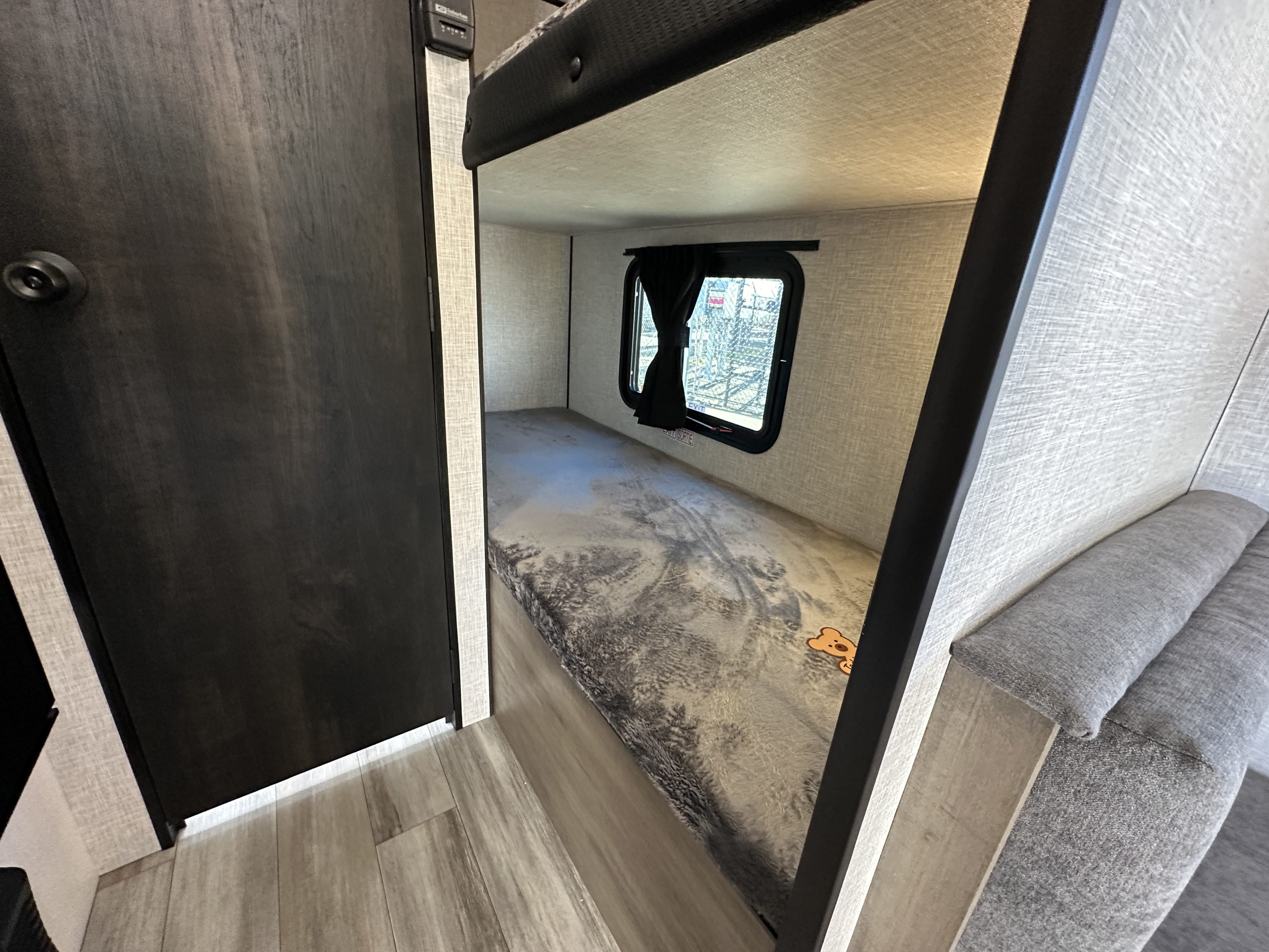 This RV rental interior showcases a cozy bunk bed with a window and adjacent seating, ideal for family travel.. Jayco Jay Flight 2024