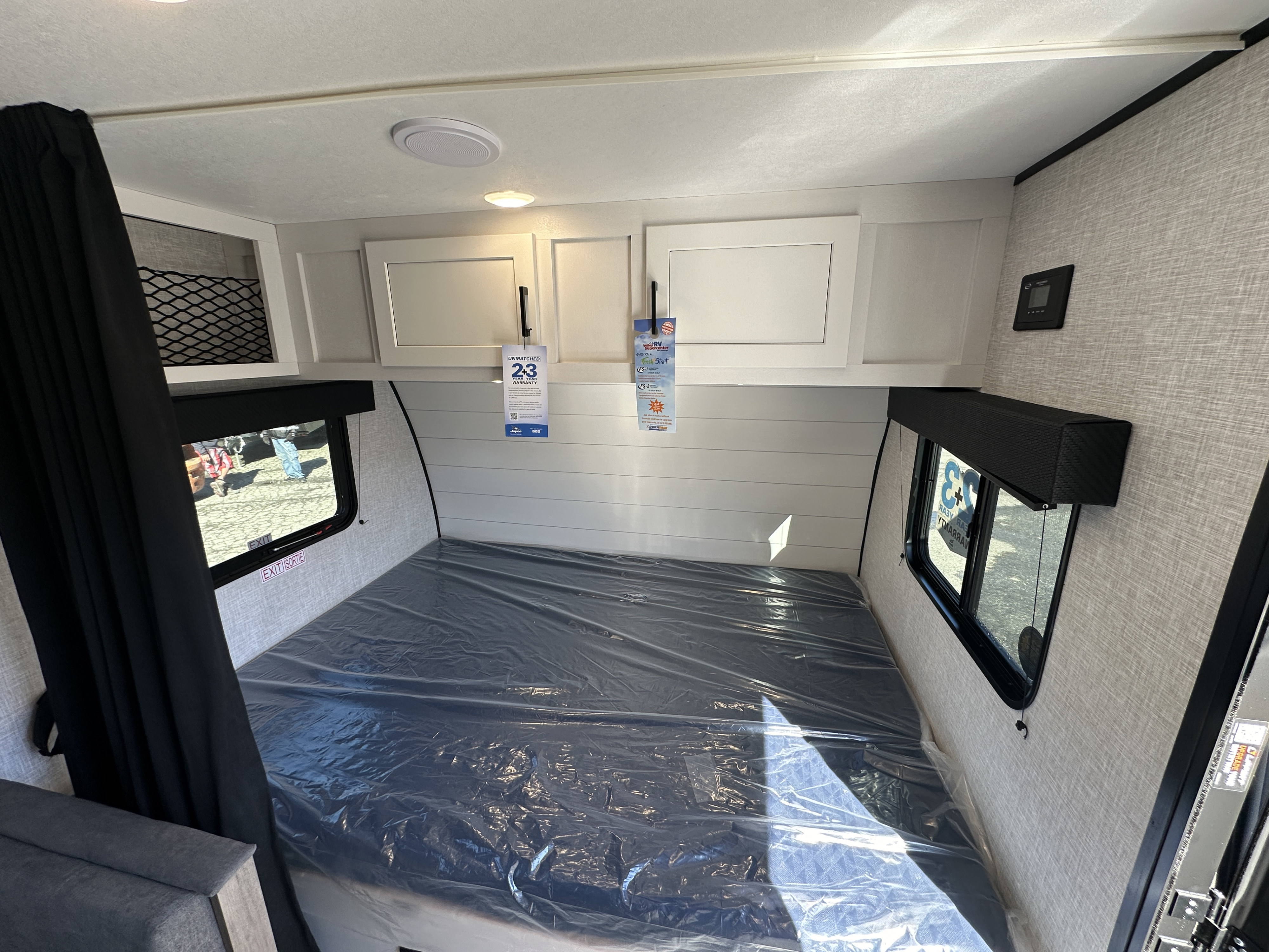 Inside a clean RV rental, featuring a protected bed, overhead storage, and windows, ready for your next travel adventure.. Jayco Jay Flight 2024