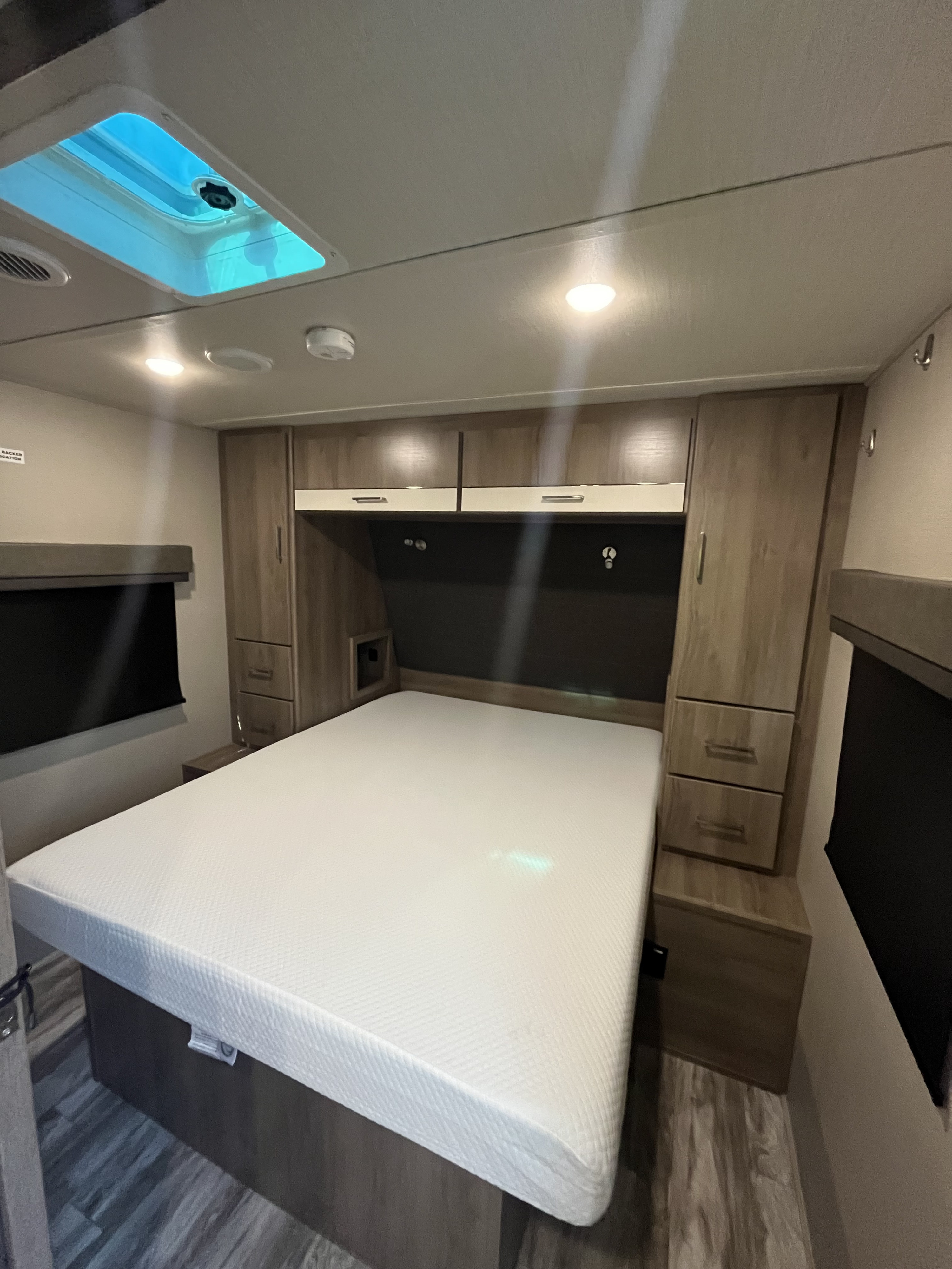 Cozy RV rental bedroom with a comfortable bed, overhead storage, and a bright skylight.. Grand Design Imagine 2022